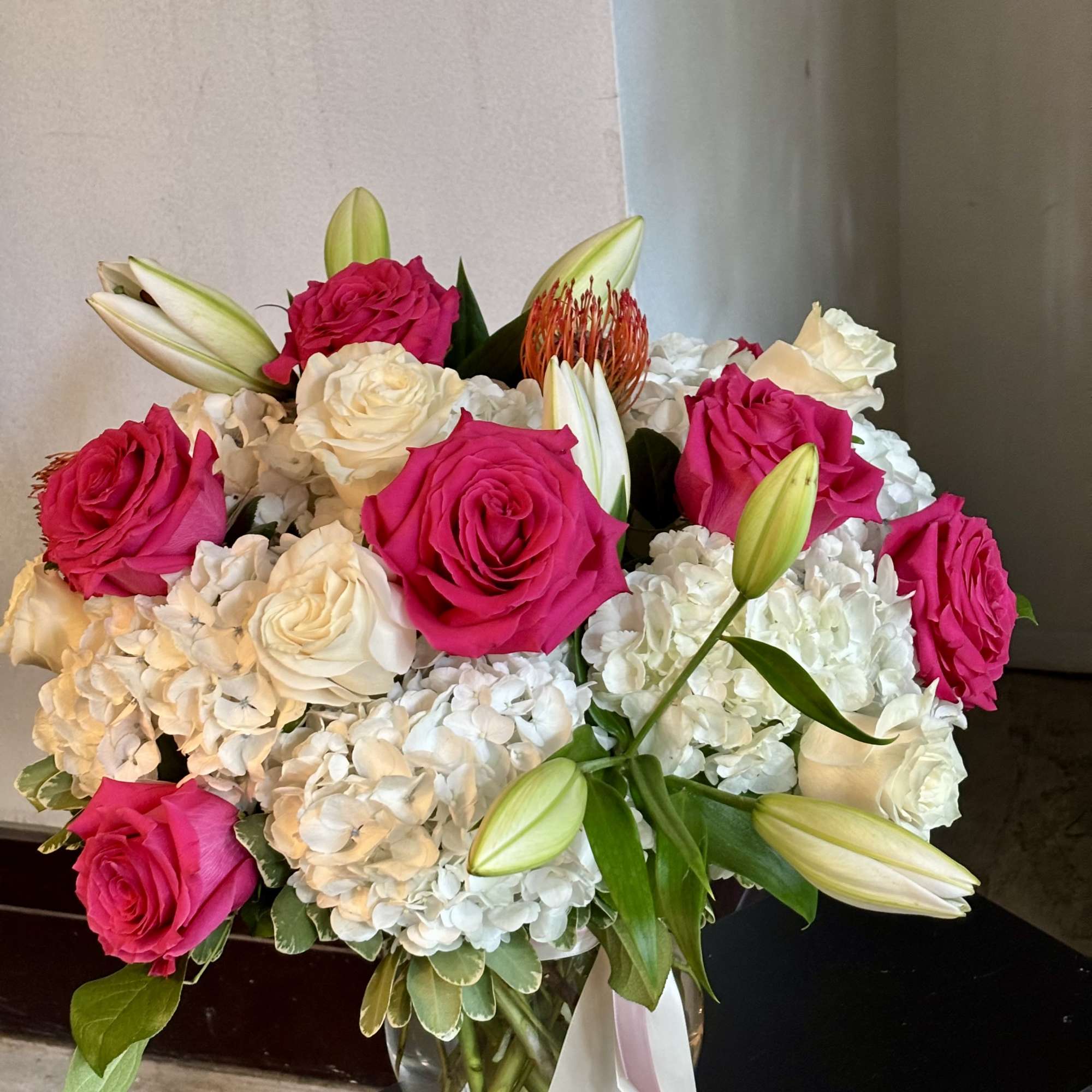 Bouquet of hot pink and white roses with lilies in a glass vase