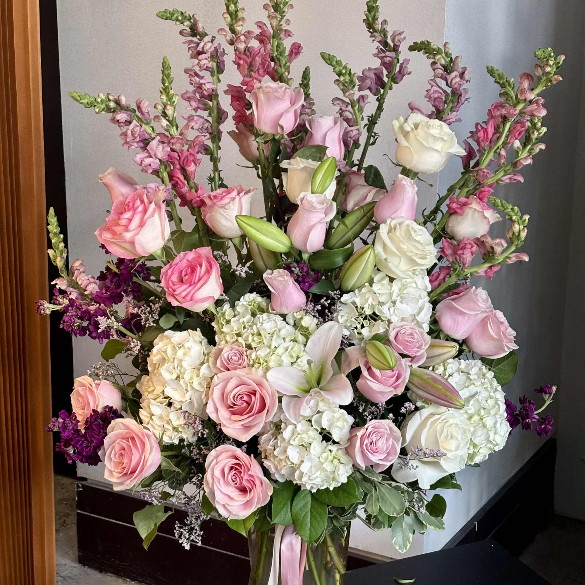 Large pink and white flower arrangement in a glass vase