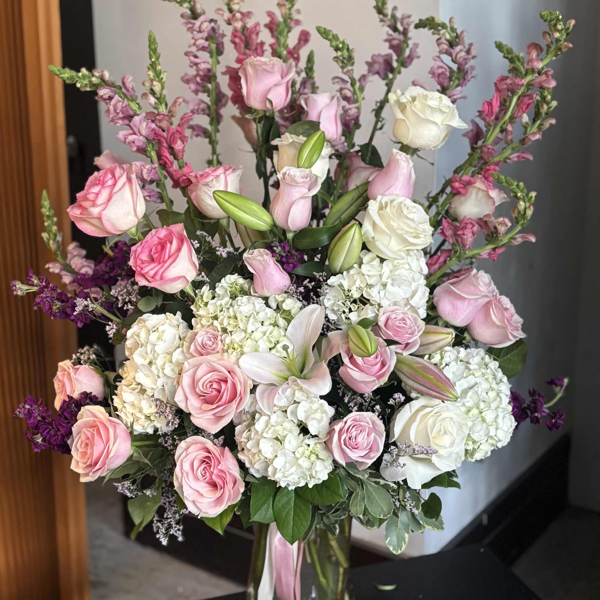 Pink and white rose bouquet with lilies and snapdragons in a glass vase