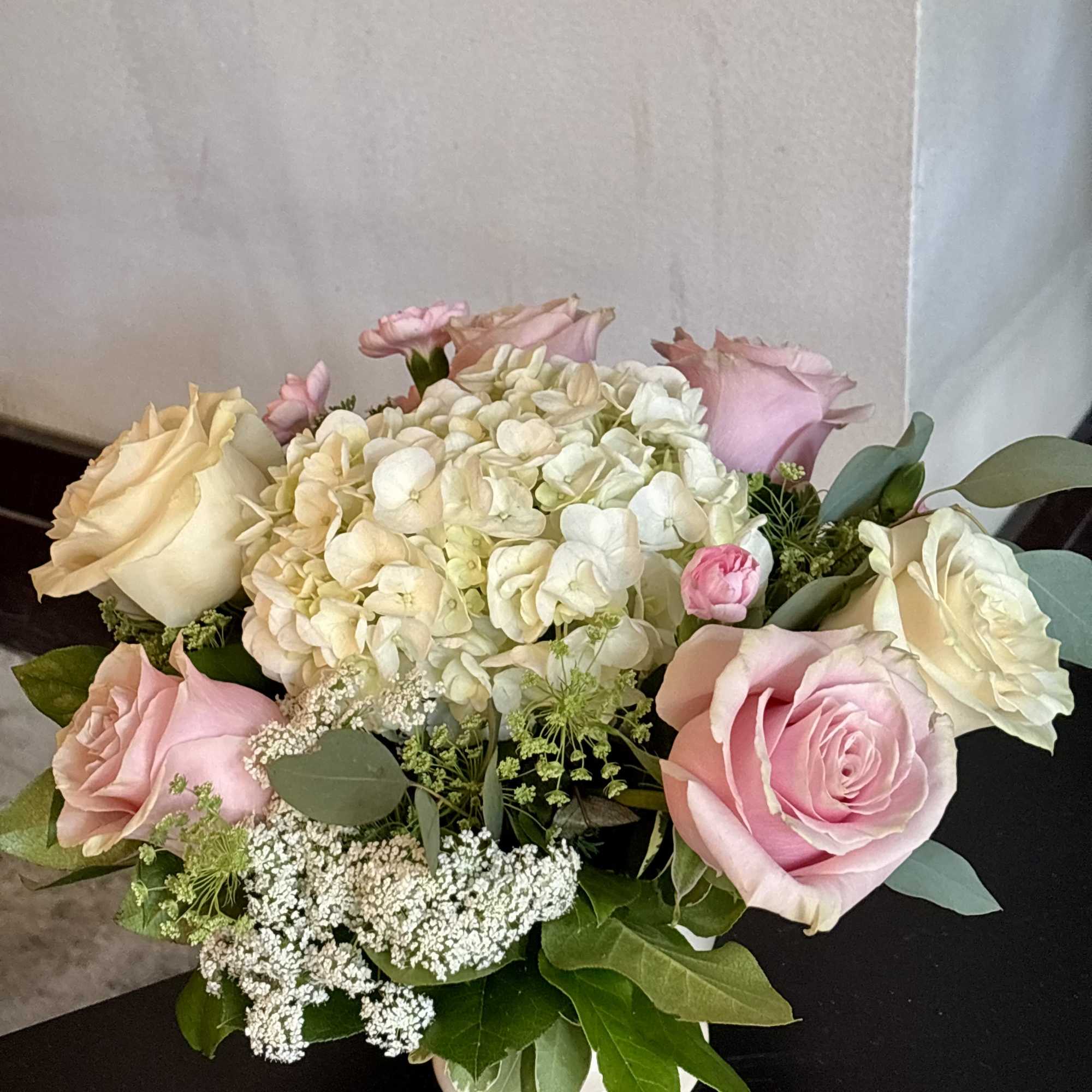 Pink and cream roses with white hydrangea in a low vase arrangement