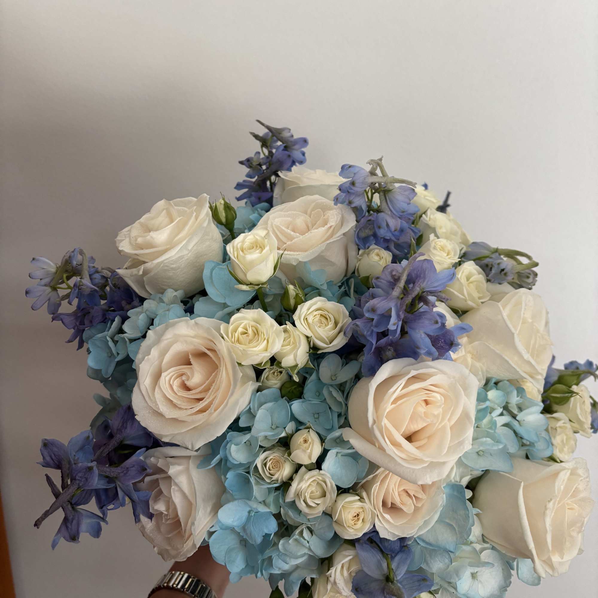 Bouquet of cream roses, blue hydrangeas, and purple delphinium