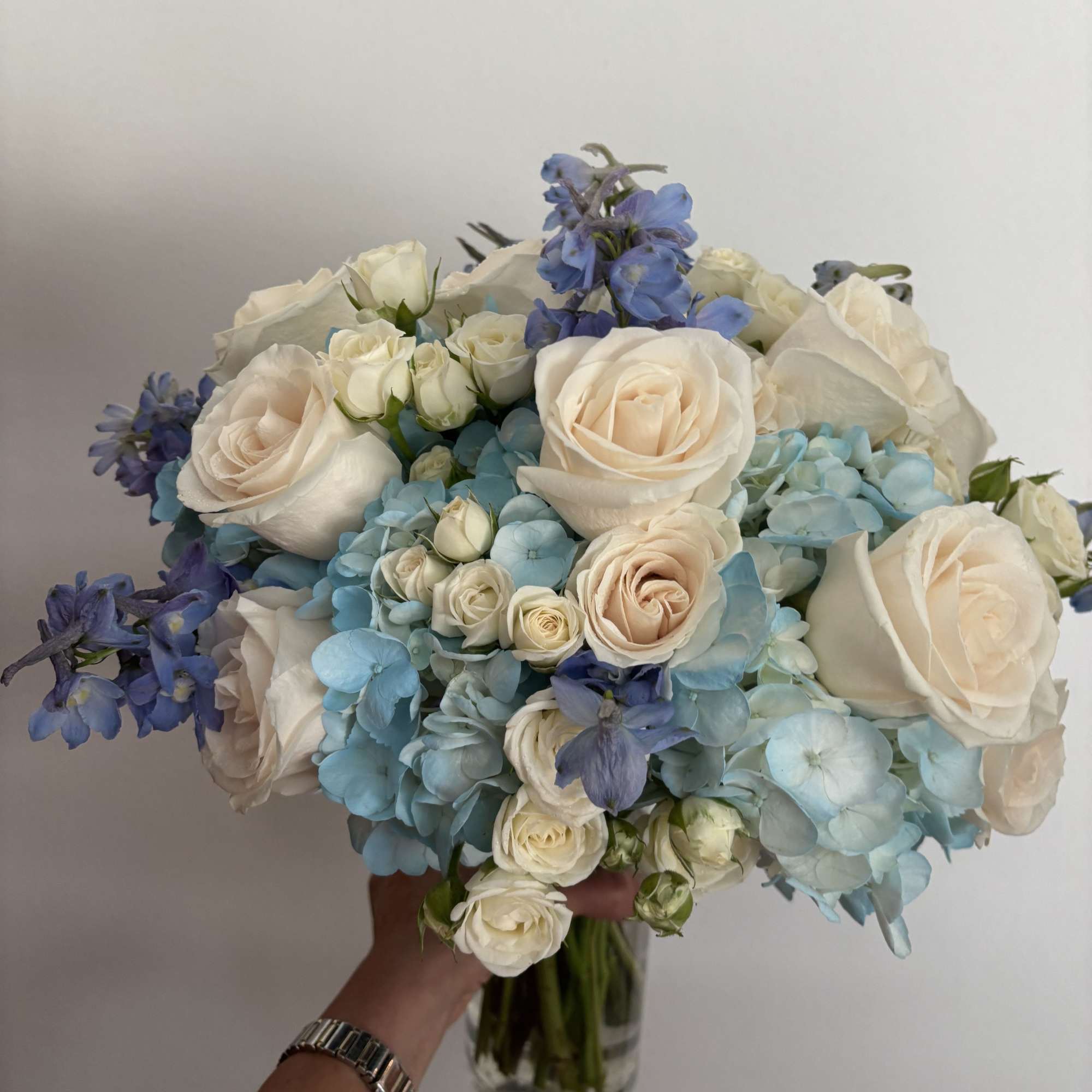 Bouquet of white roses and blue hydrangeas in a glass vase