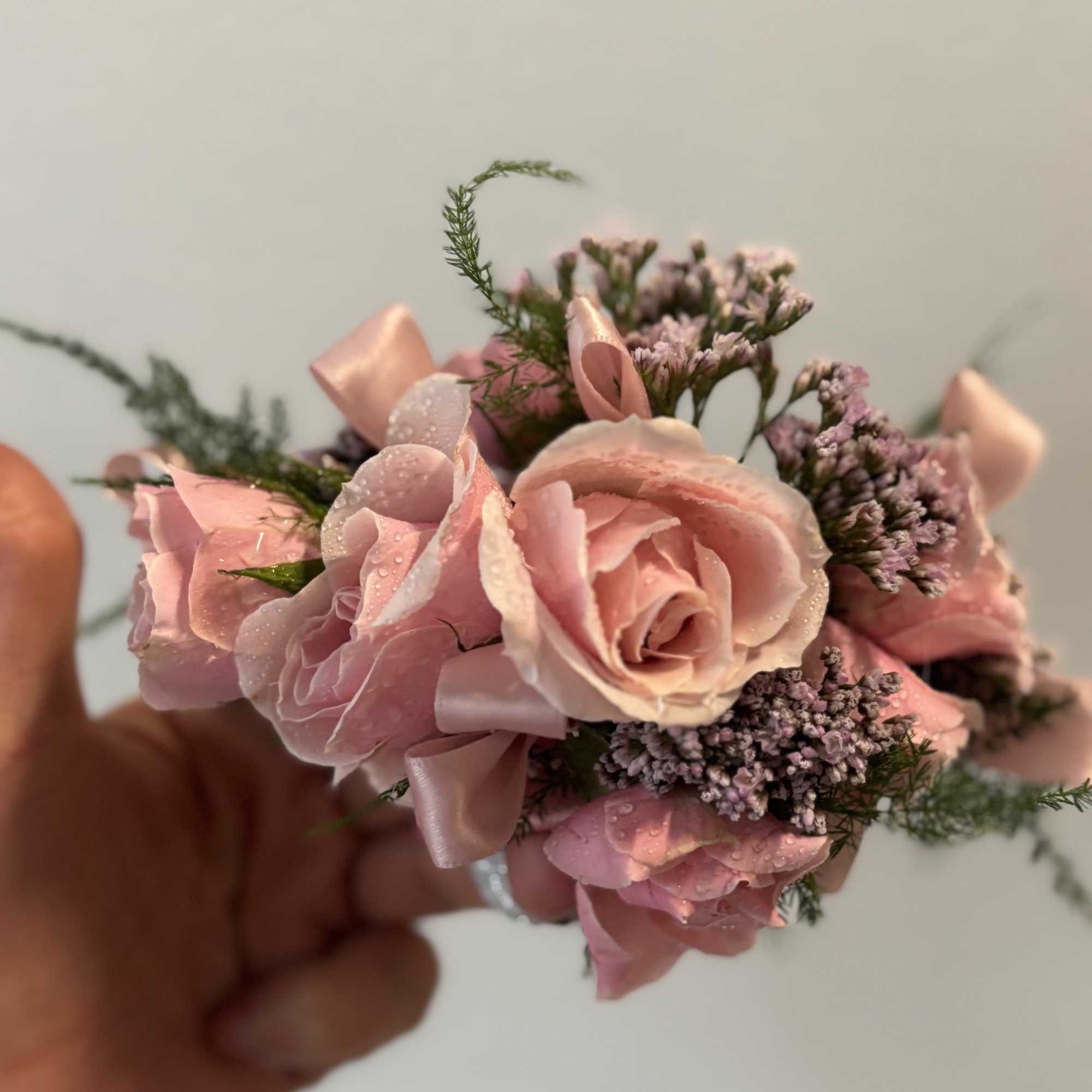 Small pink rose corsage with ribbon and tiny purple filler flowers
