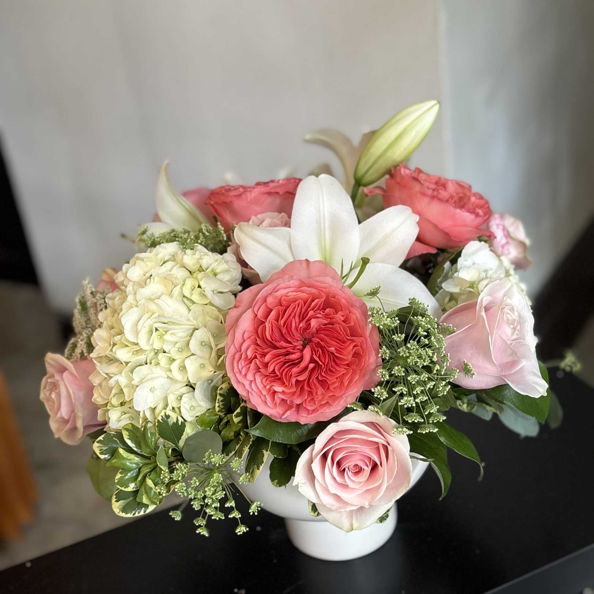 Pink and white rose arrangement with a white lily in a vase