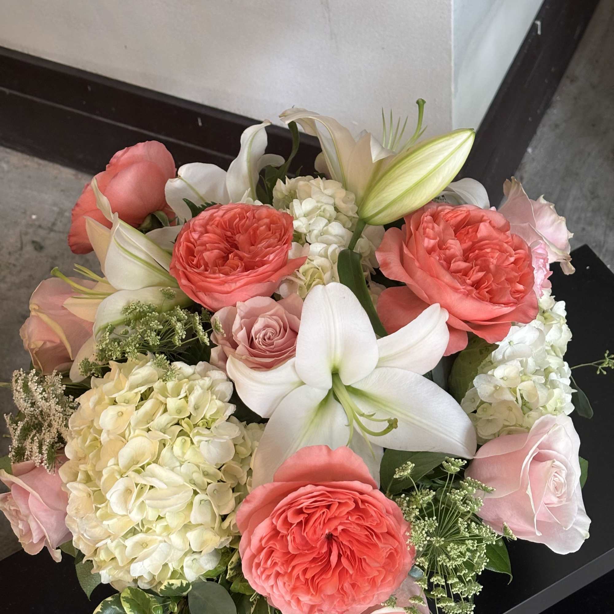 Bouquet of coral and blush roses with white lilies and hydrangeas
