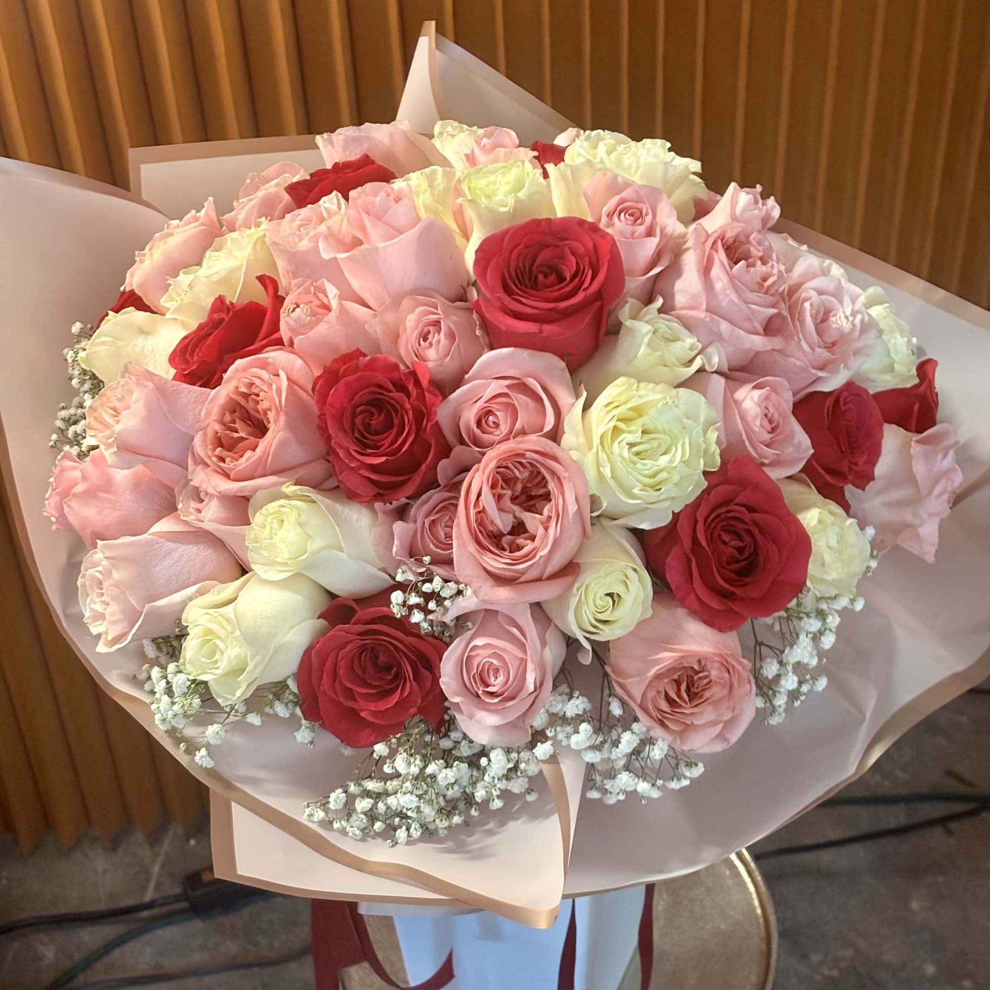 Bouquet of pink, red, and white roses wrapped in pale paper