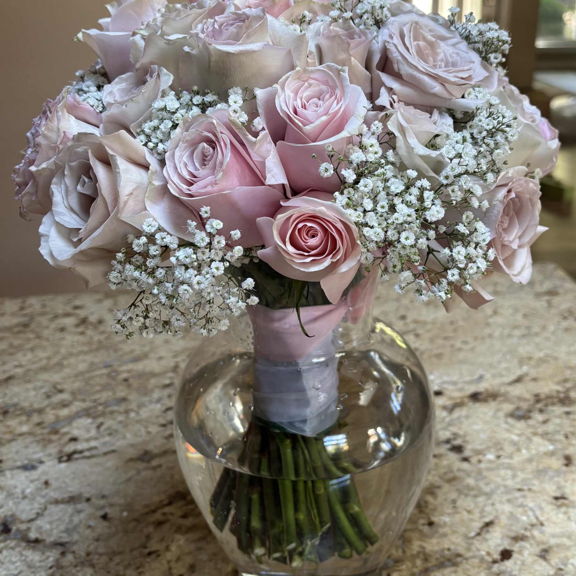 Bouquet of pale pink roses and baby's breath in a clear glass vase