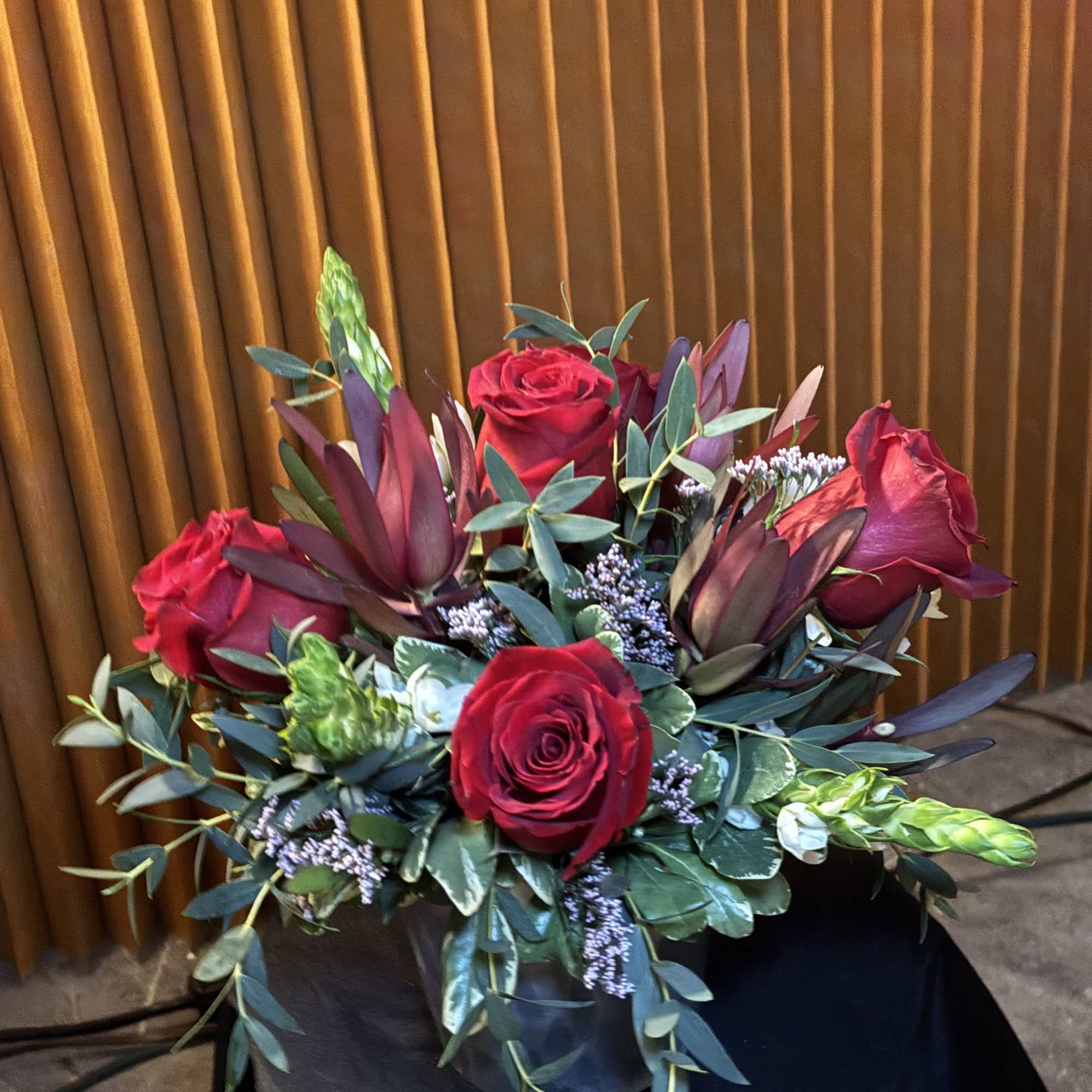 Bouquet of red roses with dark burgundy accents and greenery