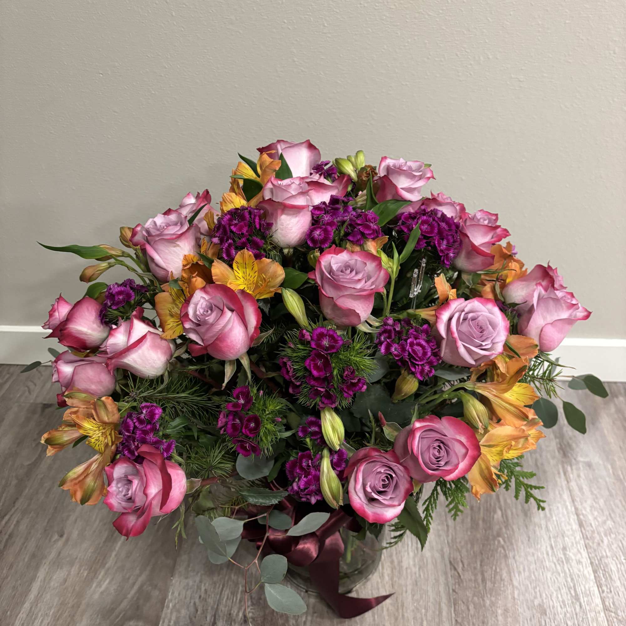 Pink roses and purple flowers arranged in a glass vase