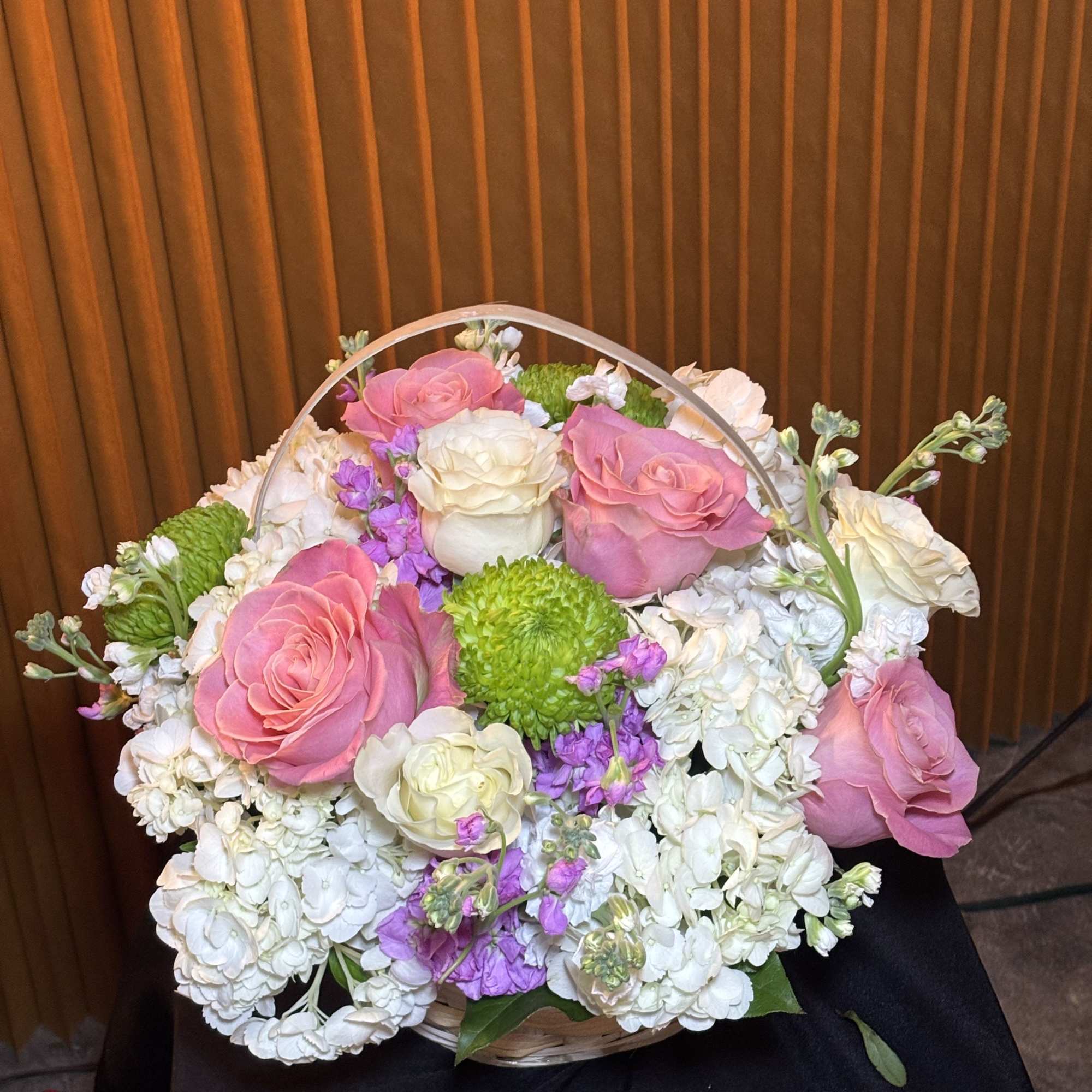 Basket arrangement of pink and white roses with white hydrangeas and purple accents