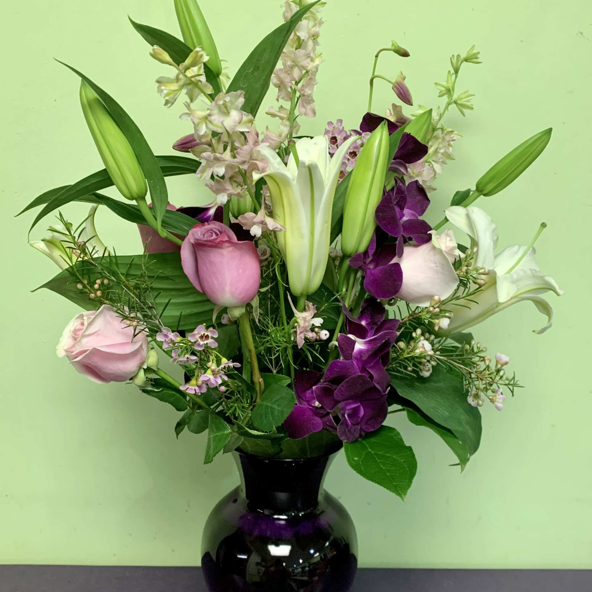 Pink roses and lilies arranged in a black vase