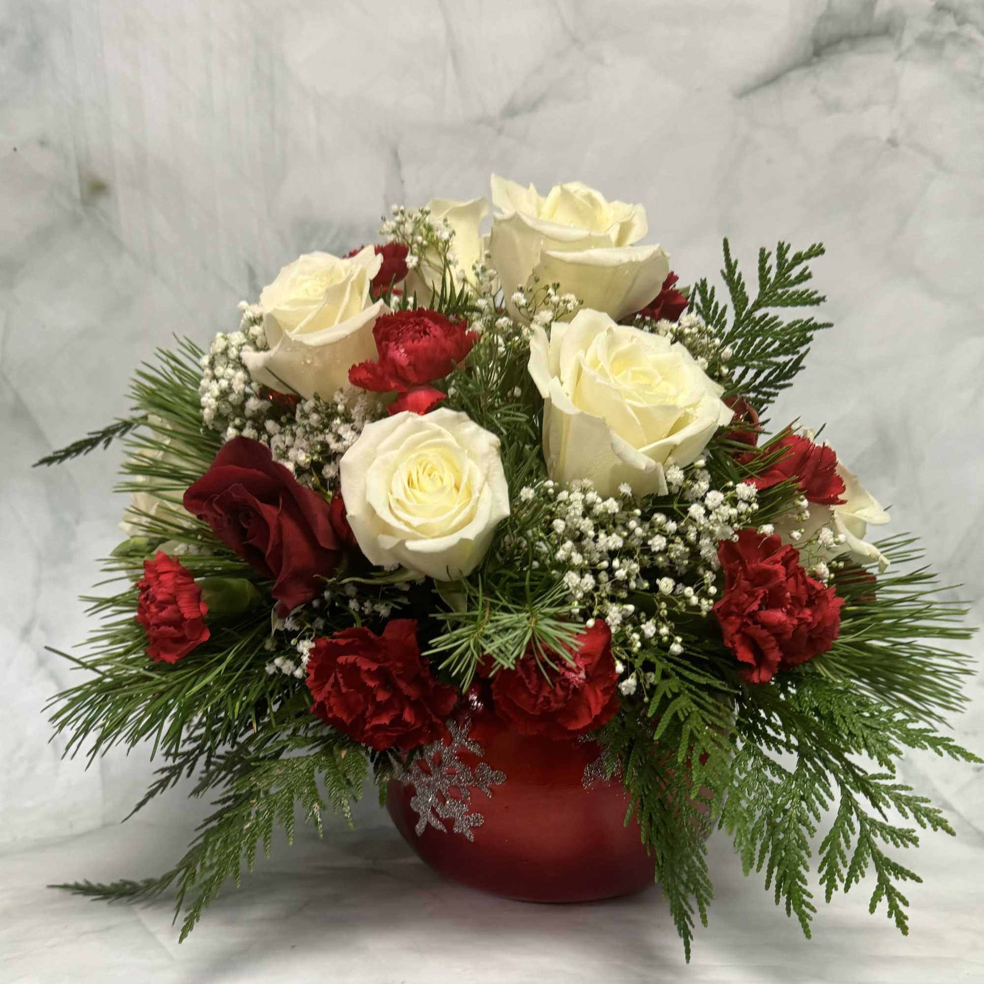 Red and white roses arranged in a red vase with greenery