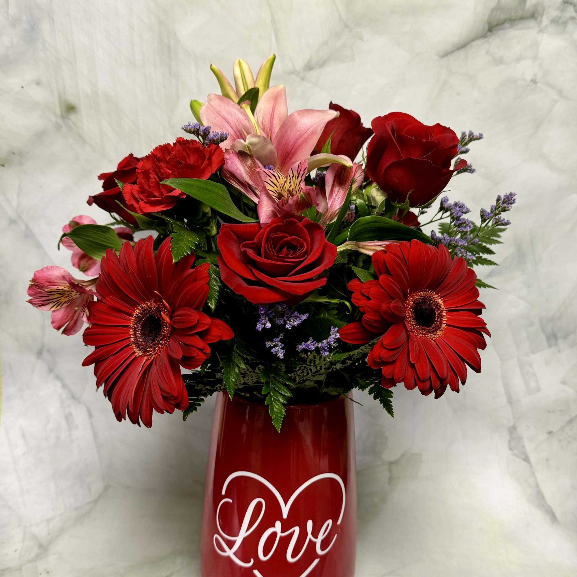 Red and pink mixed bouquet in a red vase with a heart and the word Love