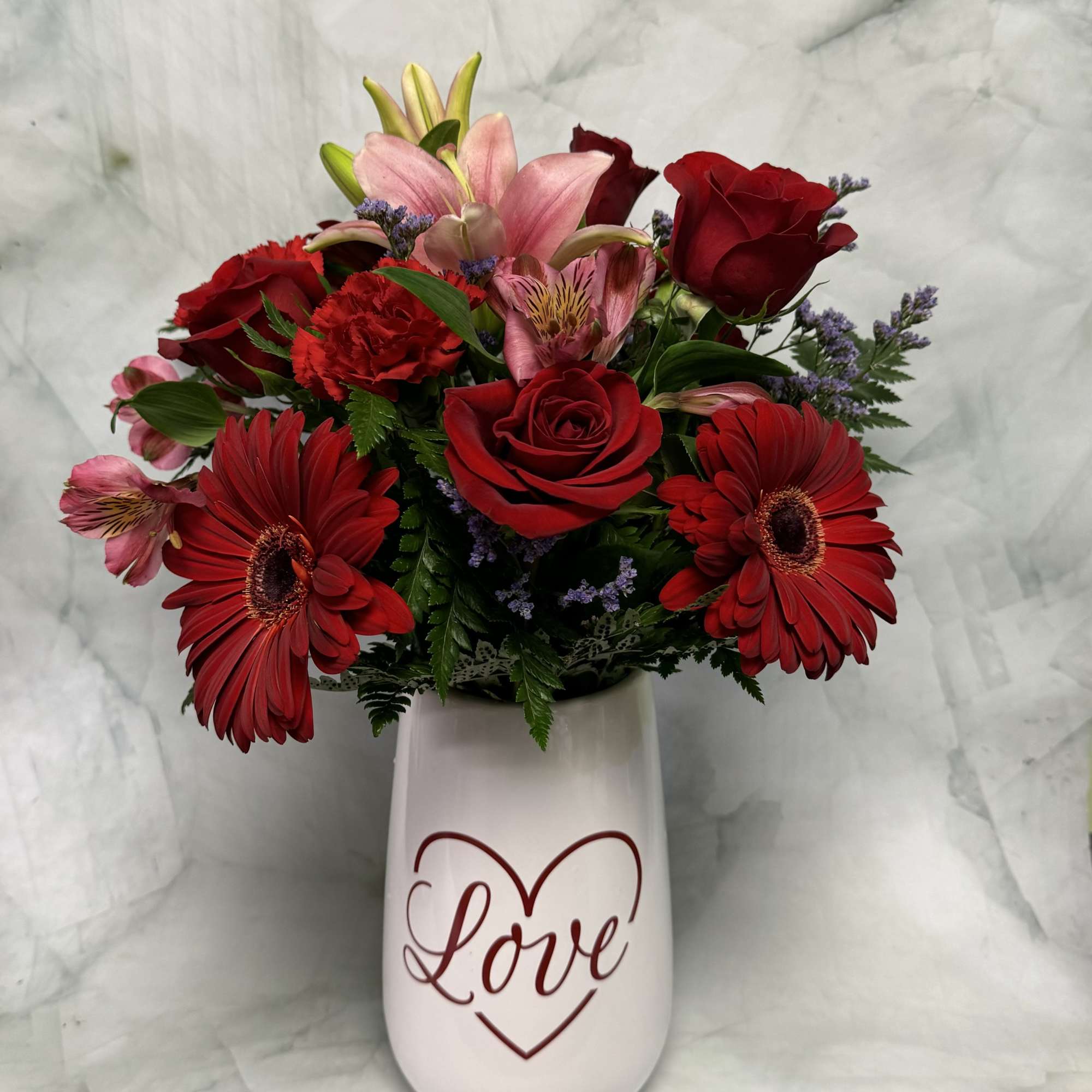 Red and pink mixed bouquet in a white vase with a Love design