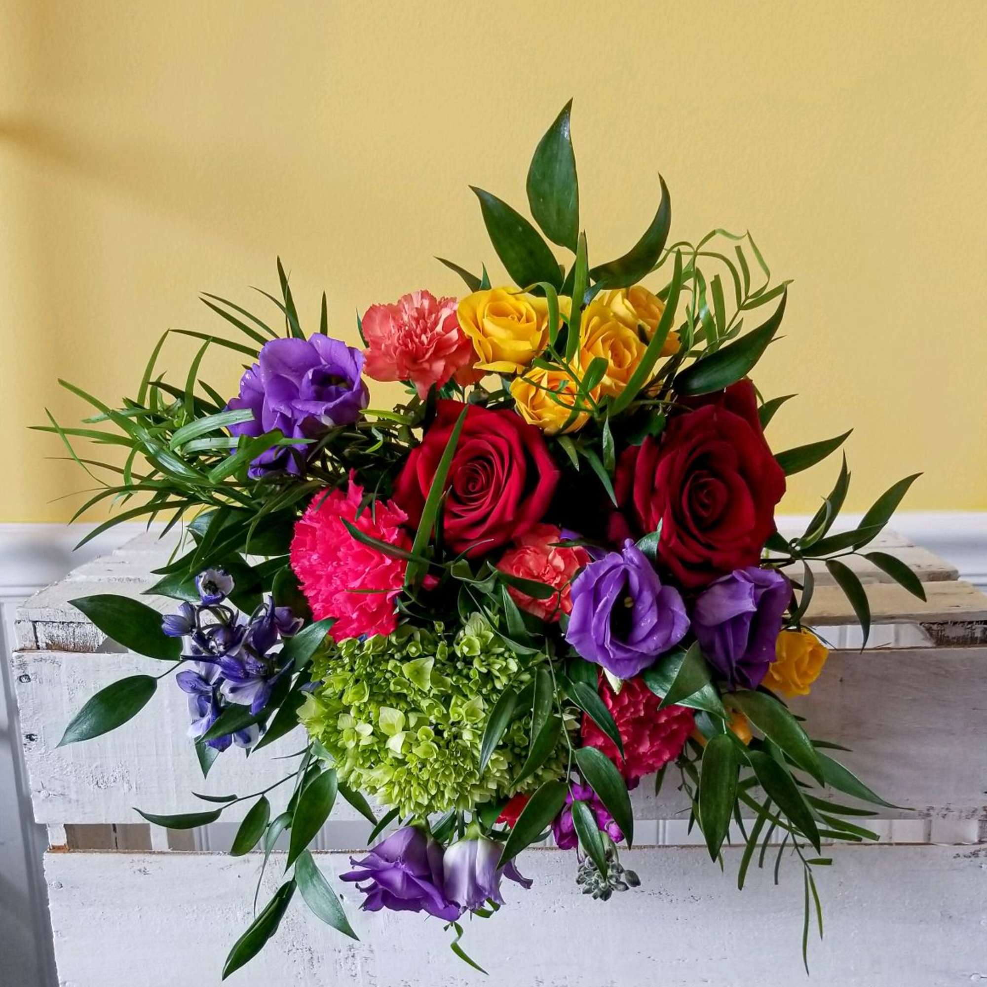 Mixed bouquet of roses, carnations, and purple blooms with greenery
