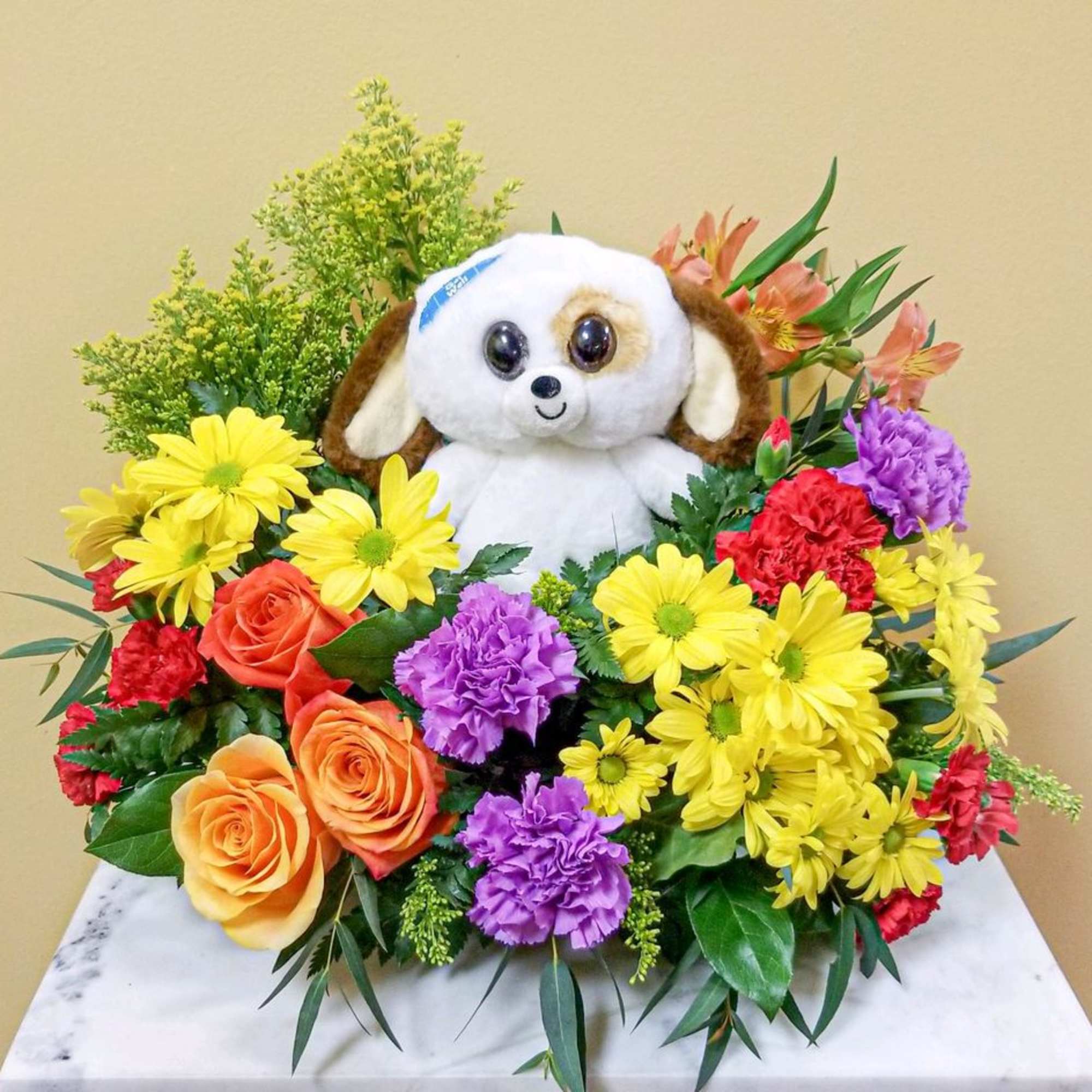 Bouquet of mixed flowers with a plush dog in the center
