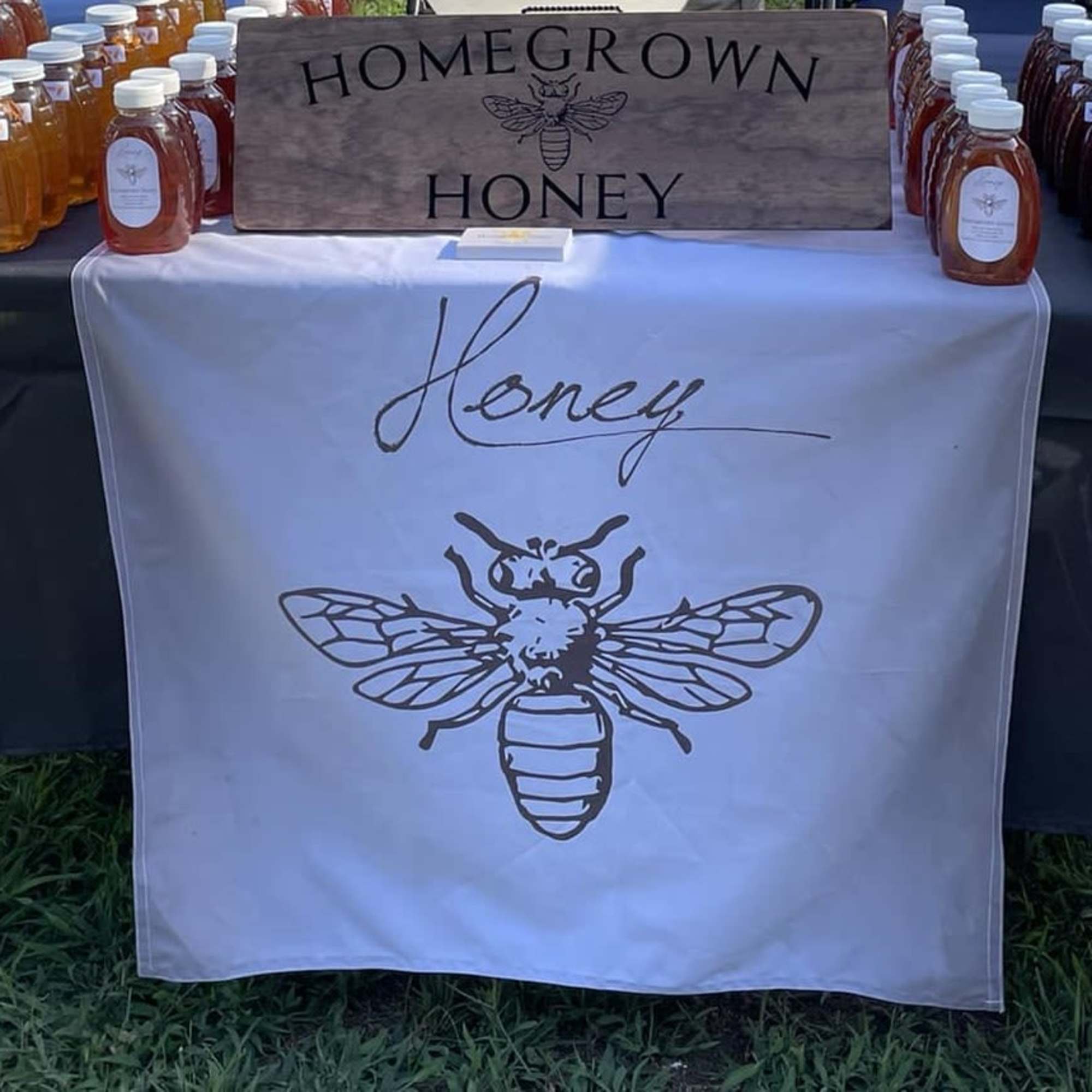 Table display of bottled honey with a bee sign