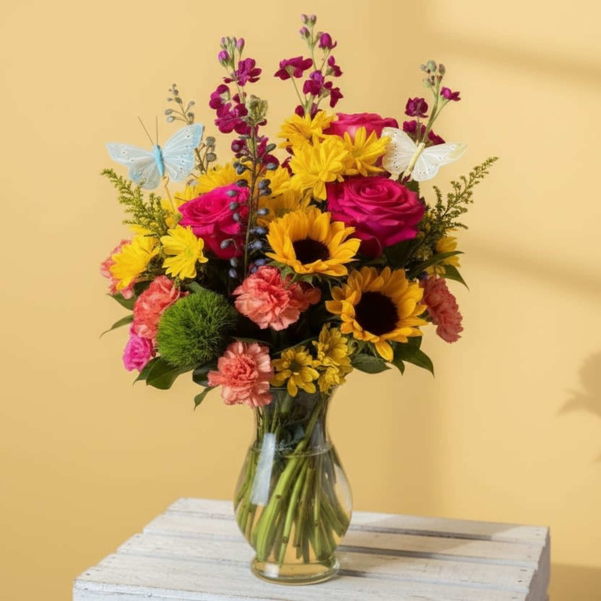 Sunflowers and hot pink roses pair with peach carnations and yellow daisies