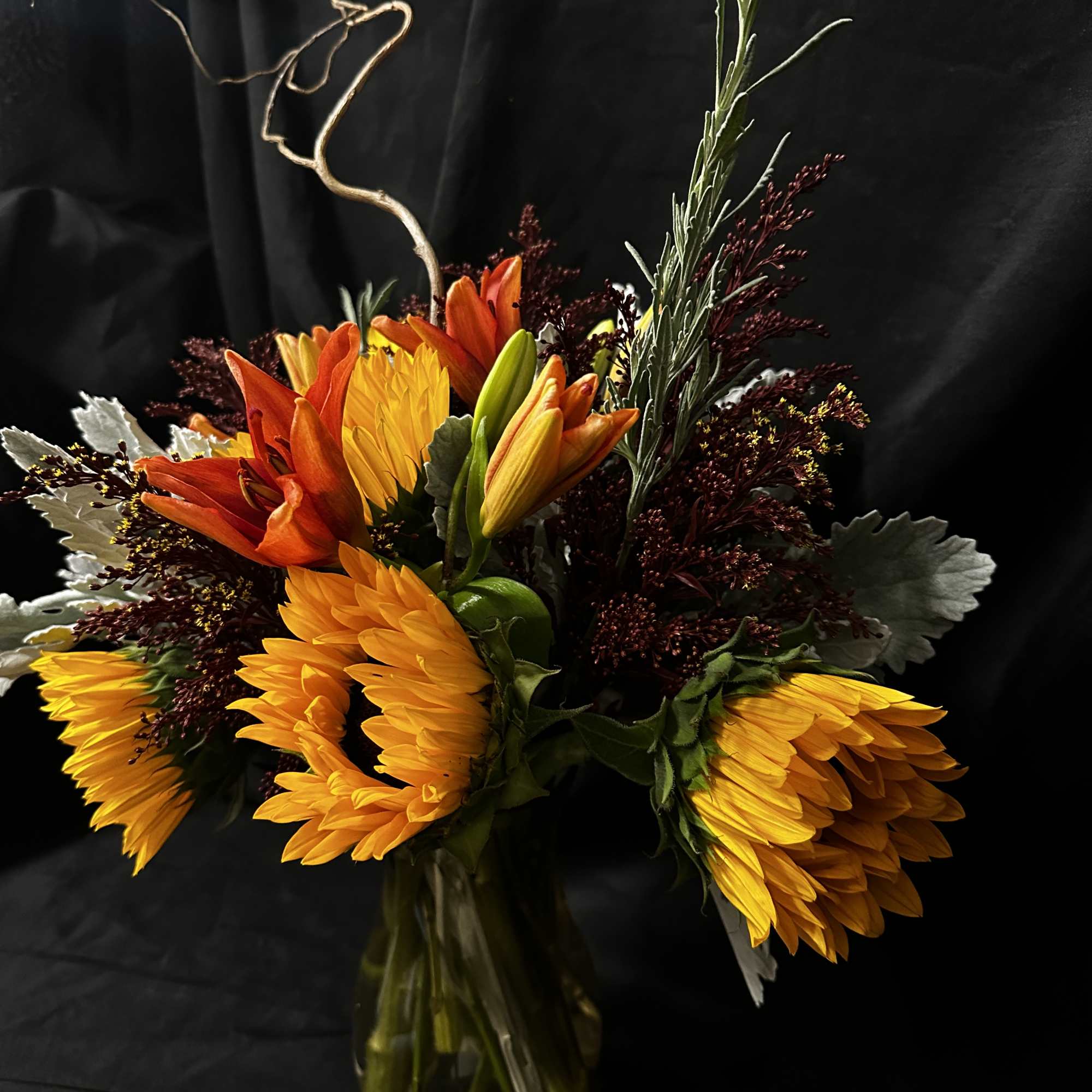 Bouquet of sunflowers and orange lilies in a glass vase