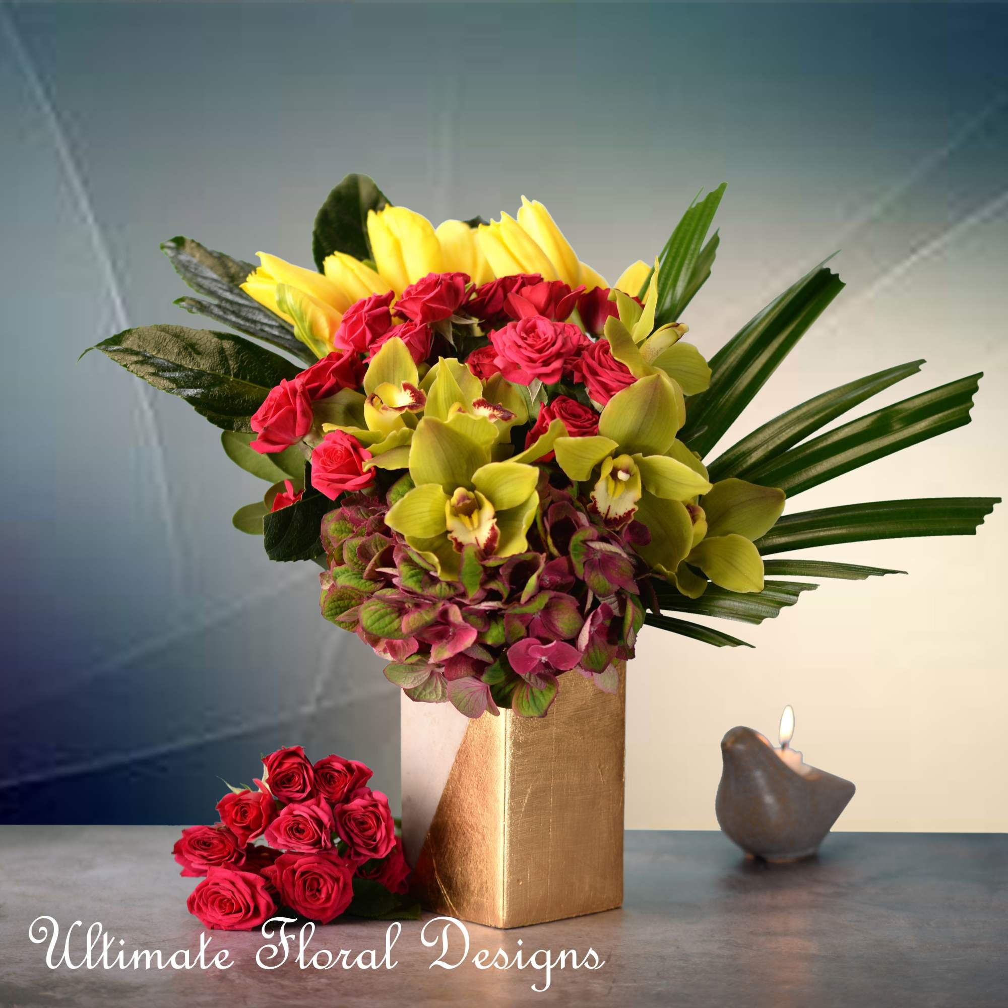 Bouquet of red roses and yellow orchids in a gold vase