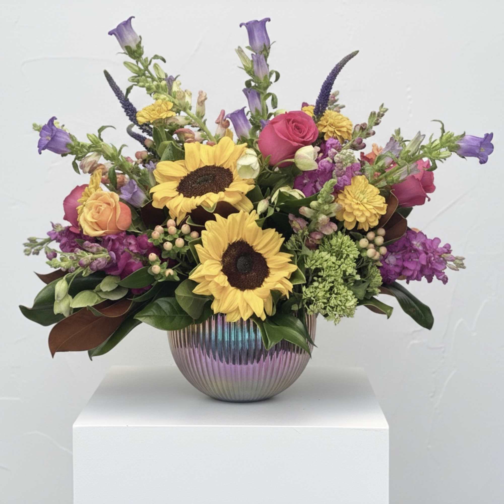 Mixed bouquet with sunflowers, roses, and purple blooms in a ribbed vase