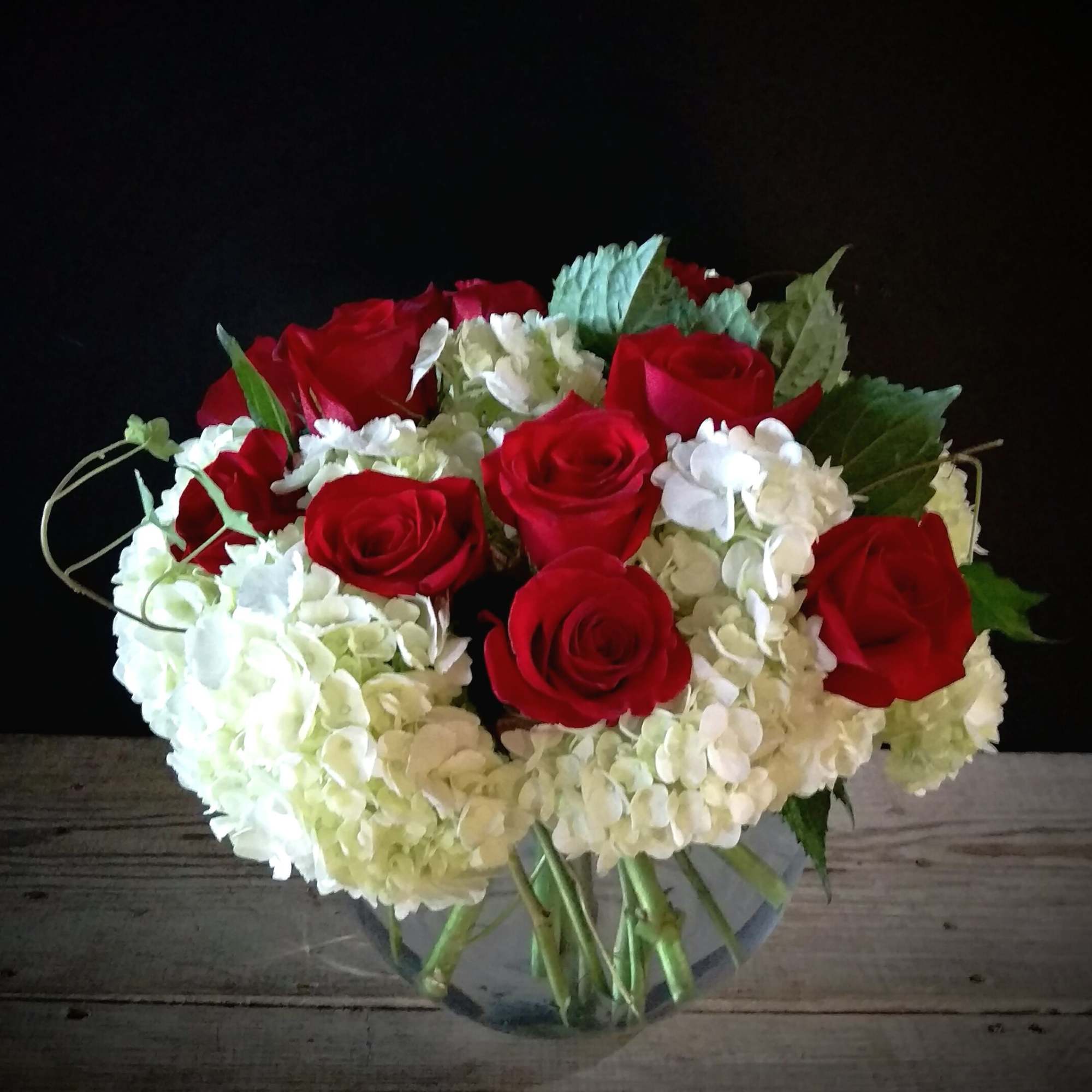 Bouquet of red roses and white hydrangeas in a clear glass vase