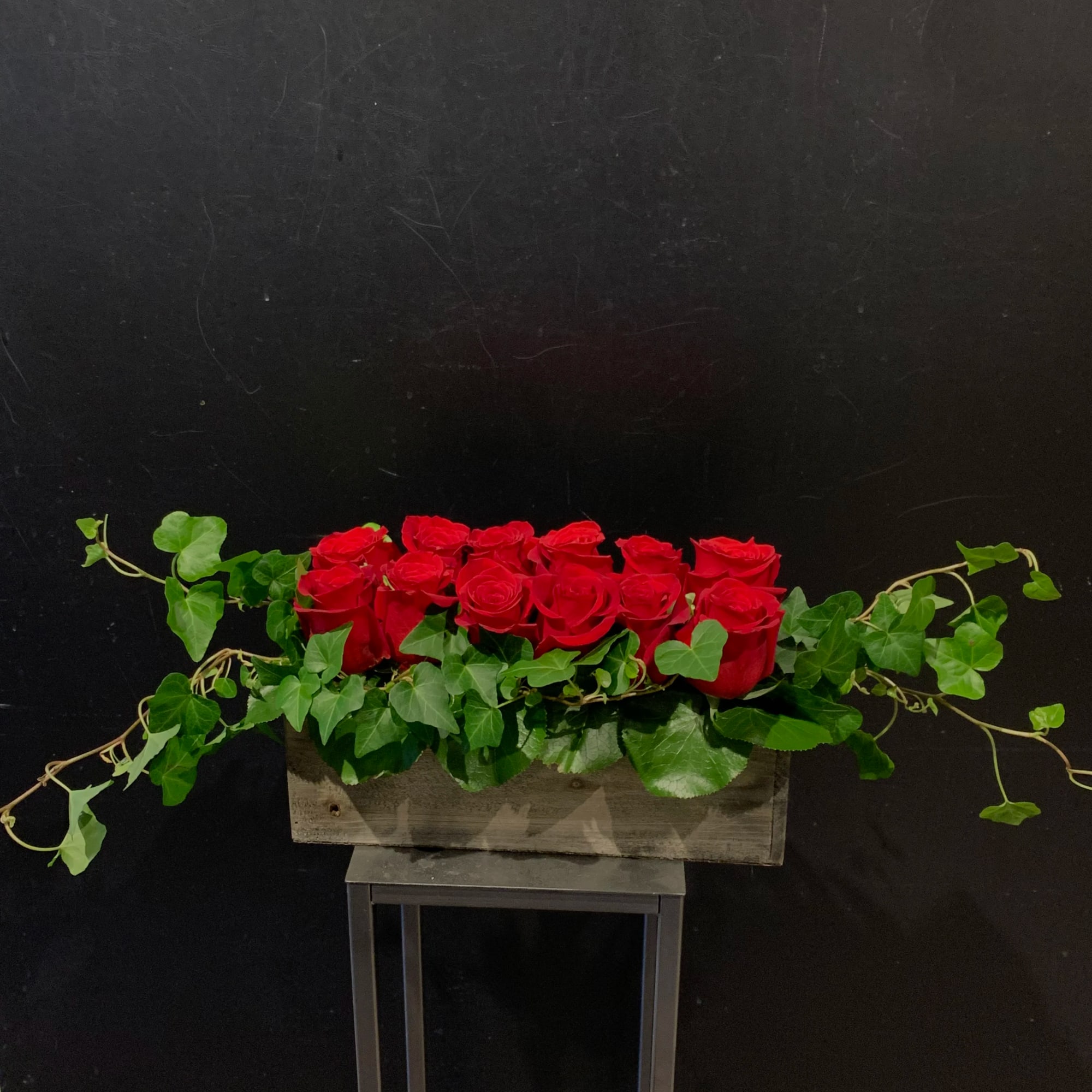 Red roses in a rectangular wooden planter with trailing ivy