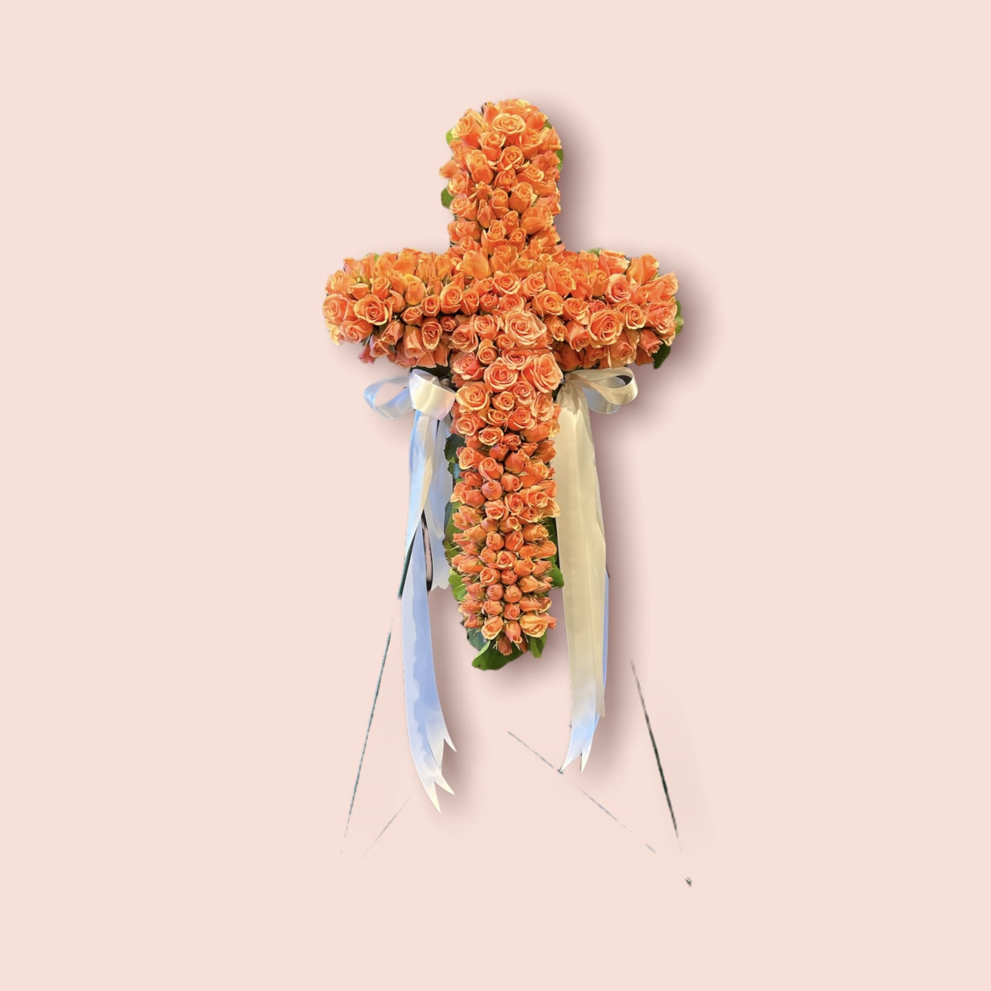 Cross-shaped arrangement of orange roses with ribbon streamers