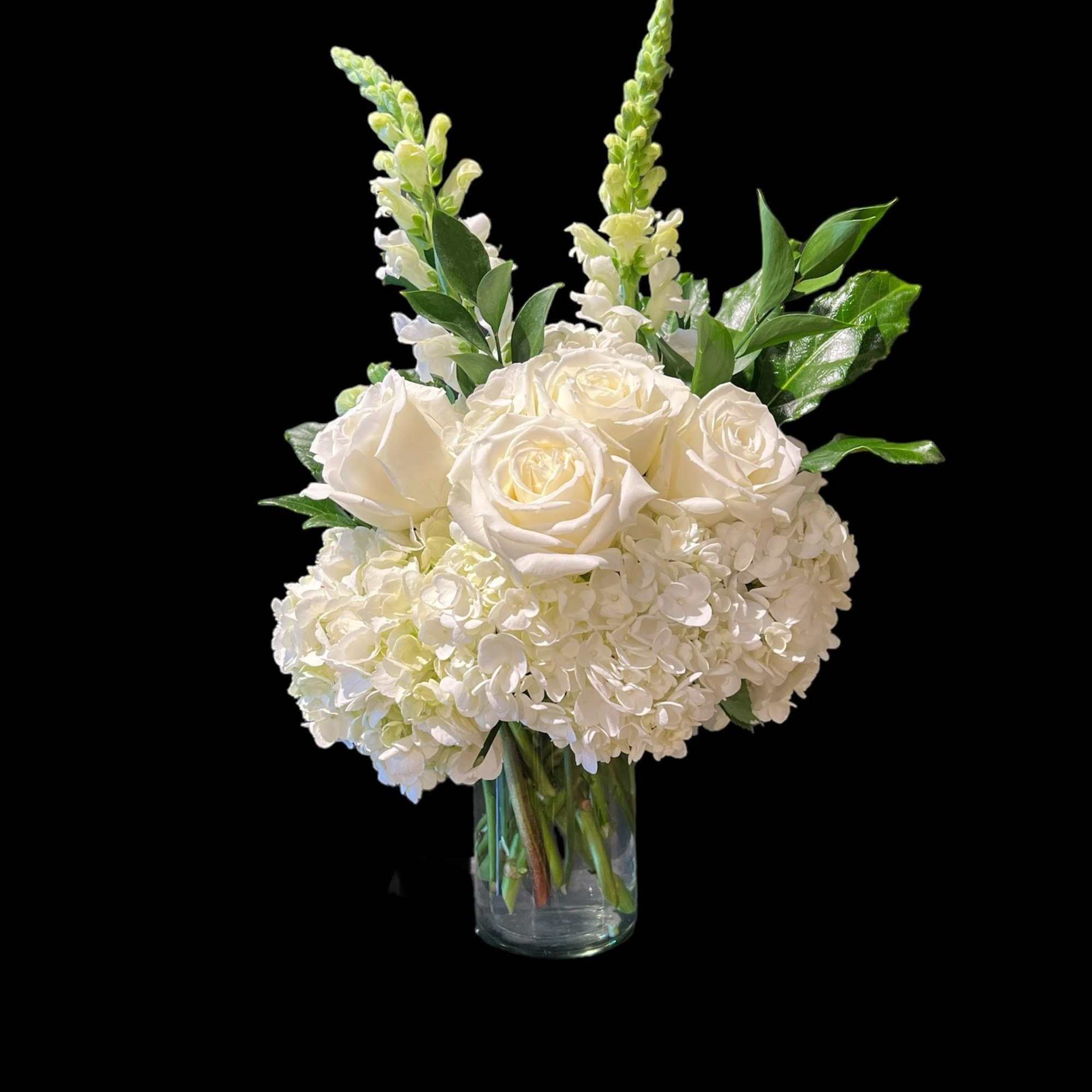 White roses and hydrangeas in a clear glass vase