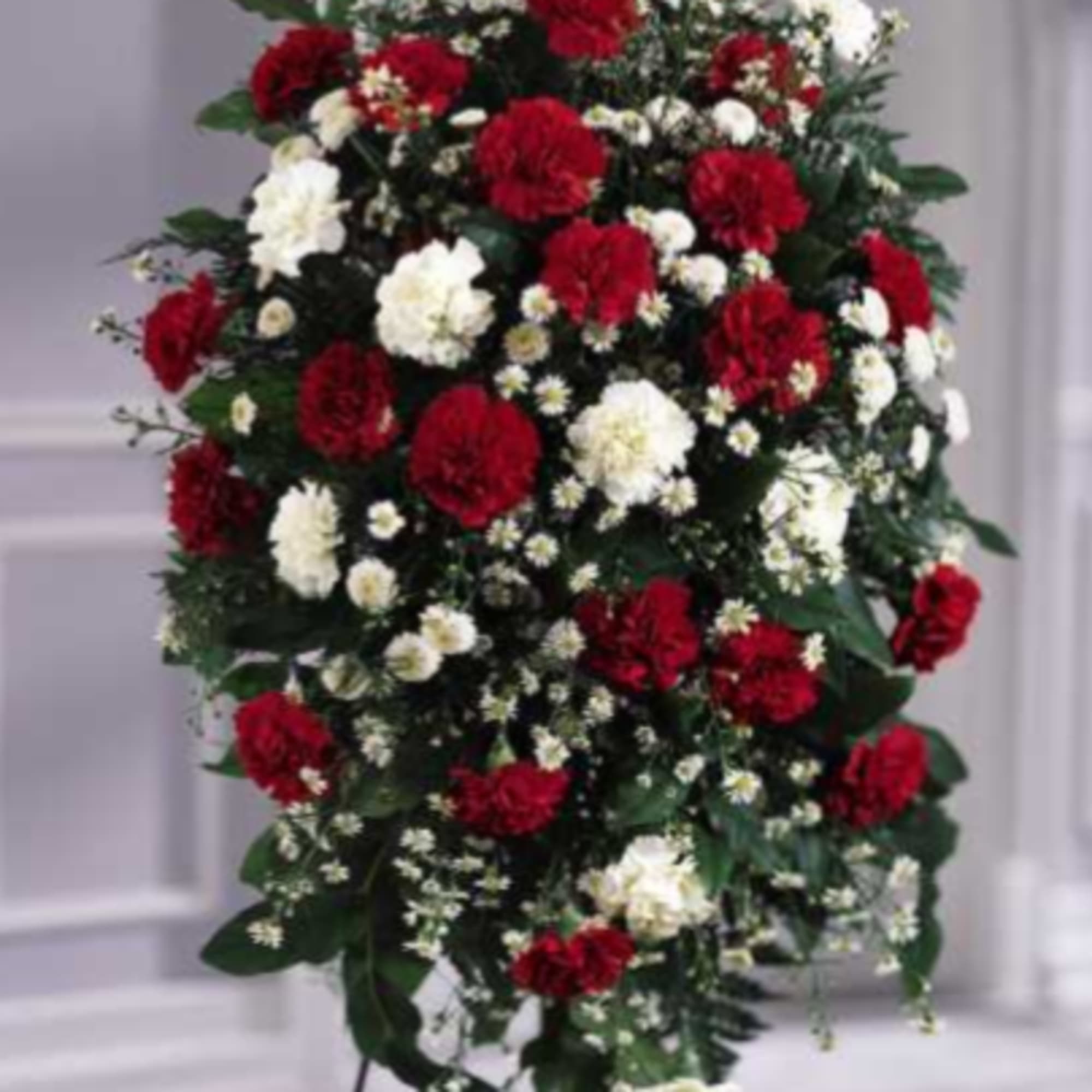Standing spray of red and white carnations on a metal easel