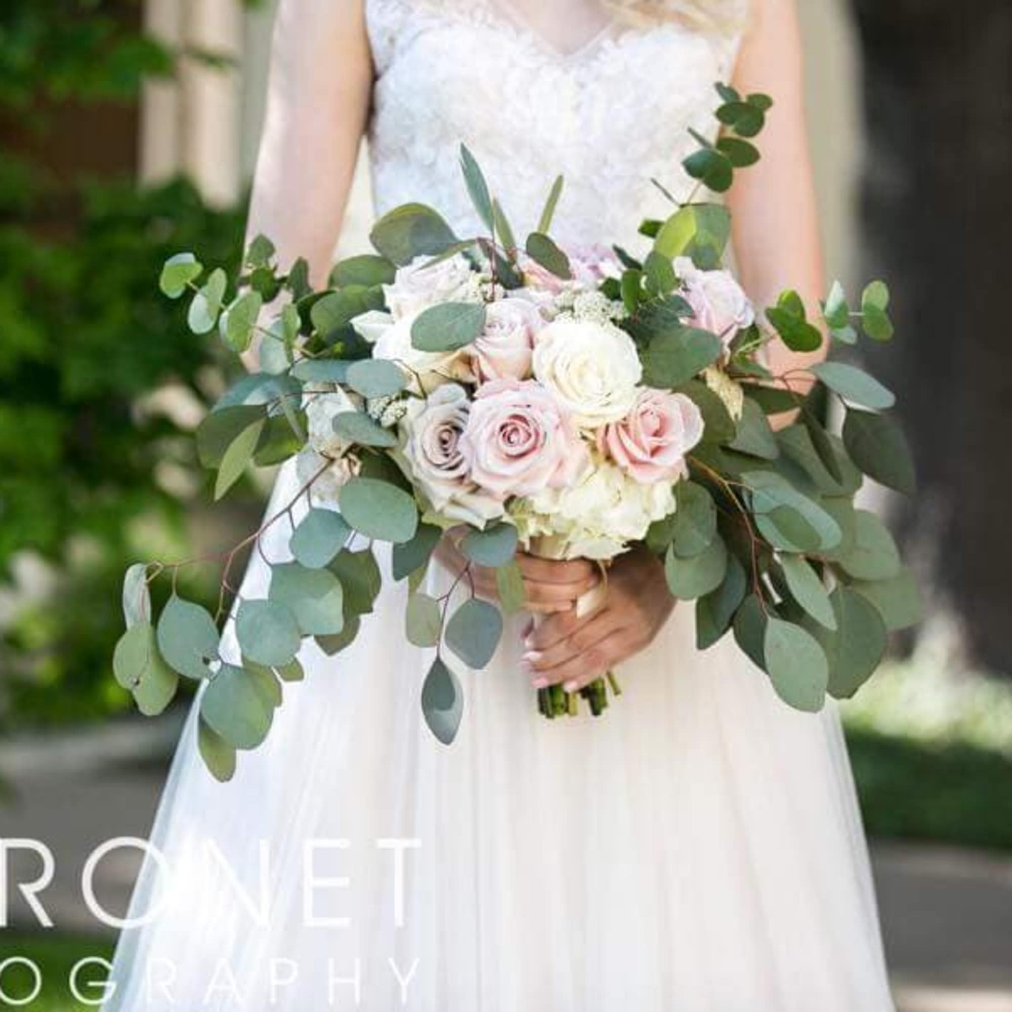 Bride holding a bouquet of pale roses and eucalyptus
