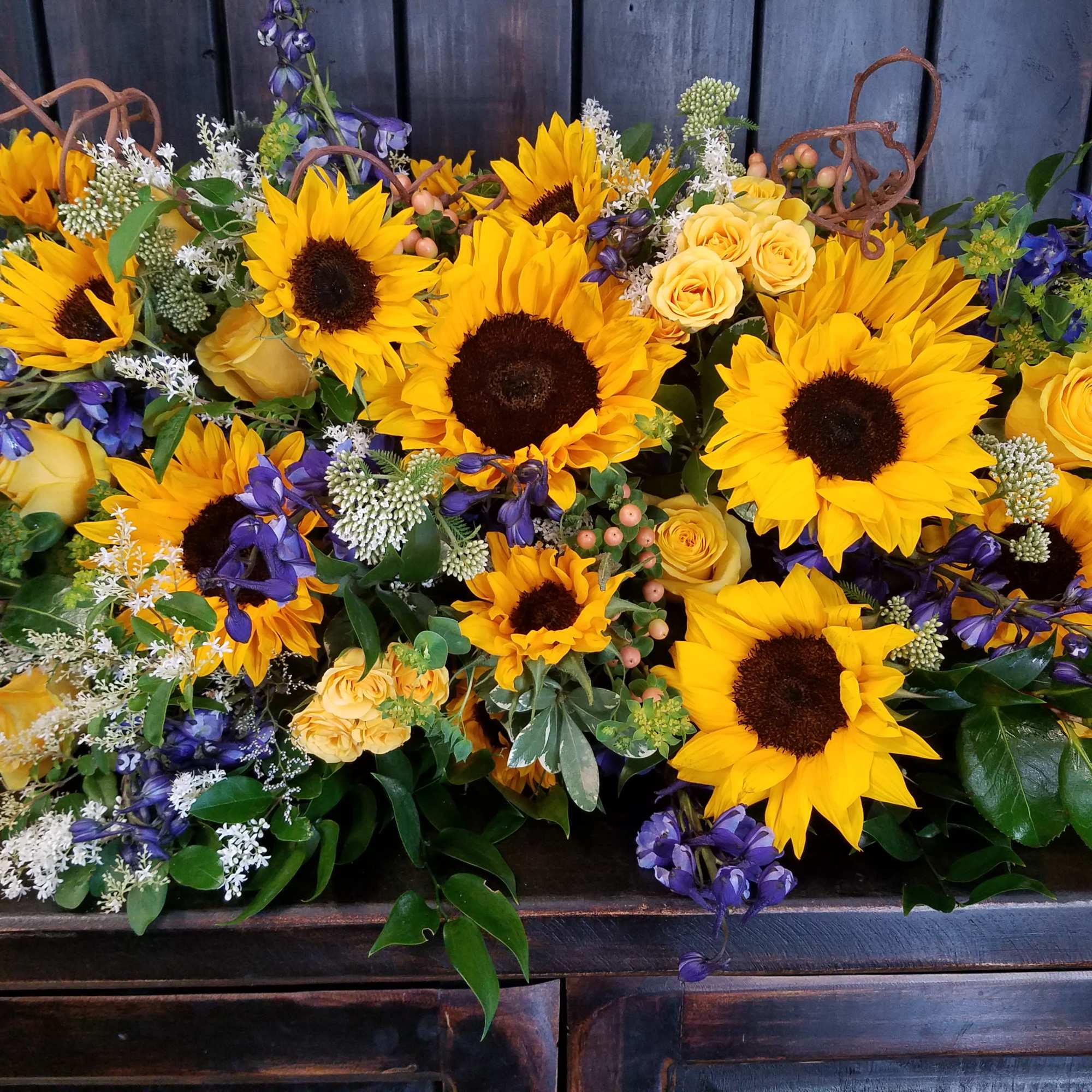 Bright sunflower and yellow rose arrangement with purple flowers
