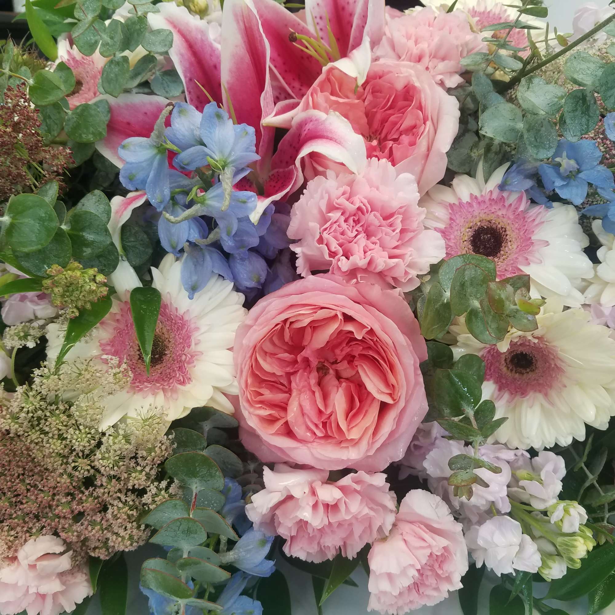 Pink roses and gerbera daisies with blue flowers in a mixed bouquet