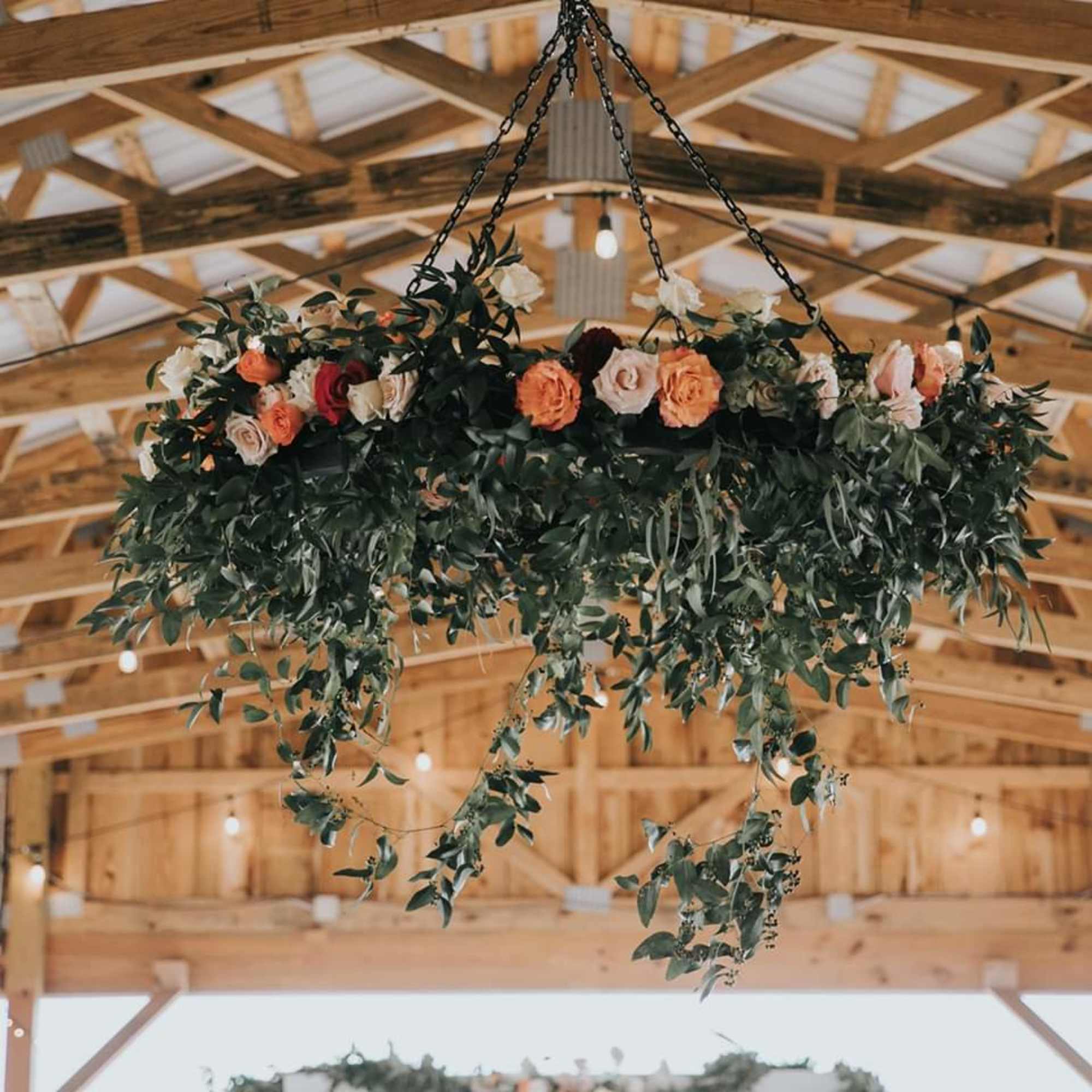 Hanging floral arrangement with roses and trailing greenery in a barn ceiling