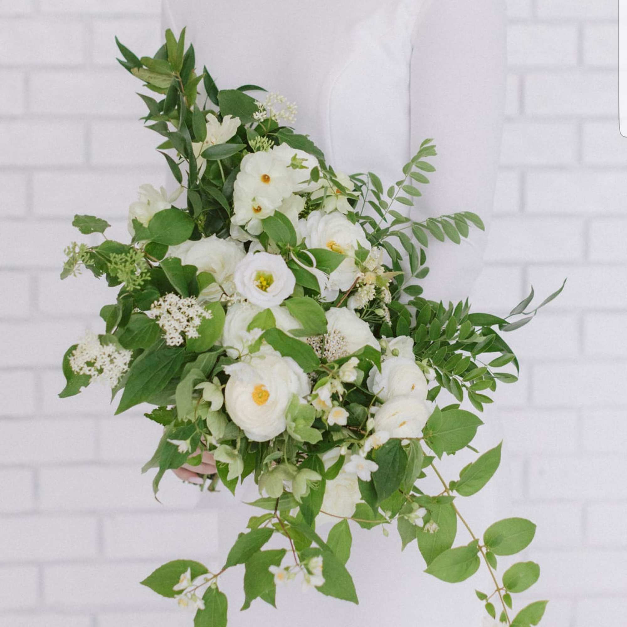 White floral bouquet with cascading greenery held by a person in a white dress