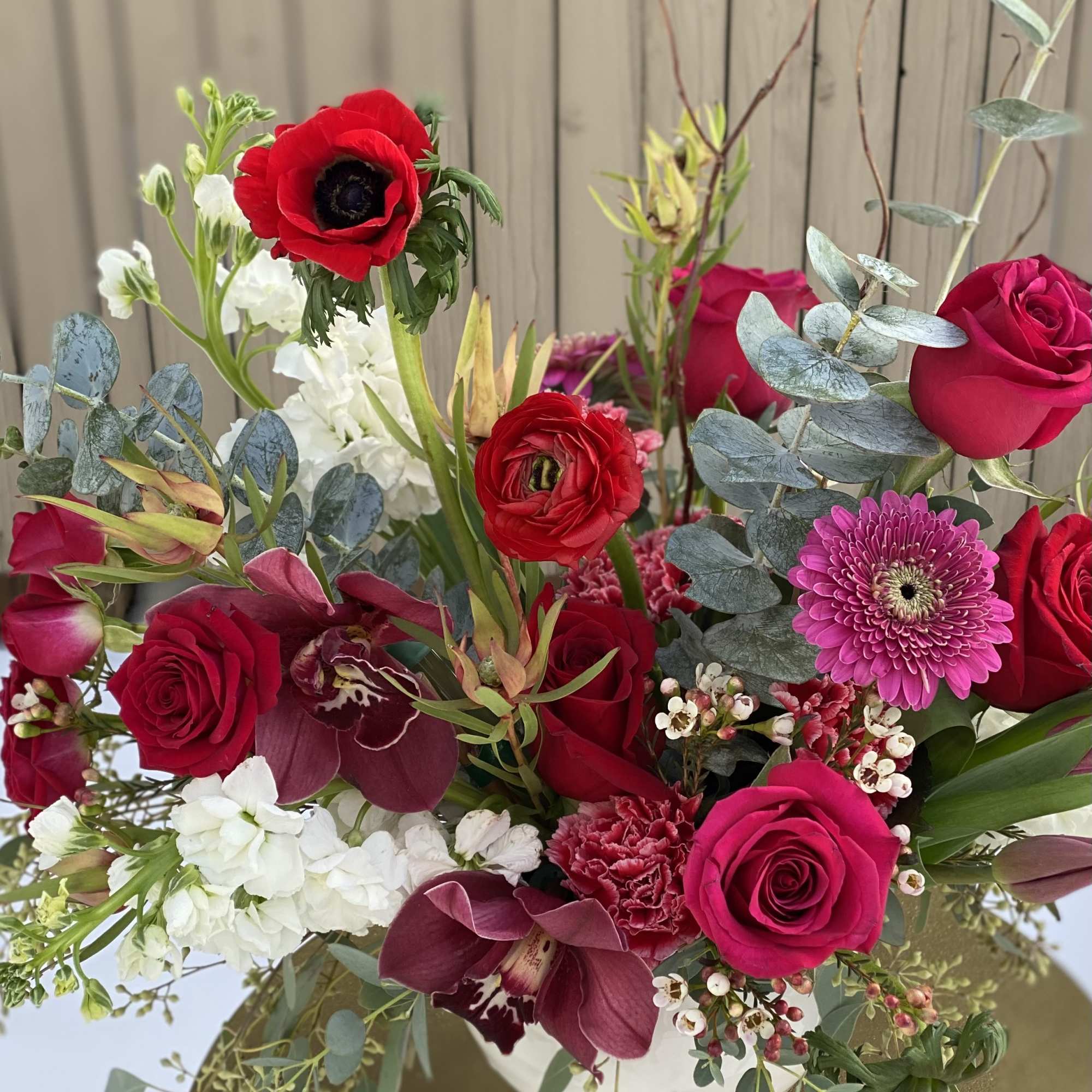 Arrangement of red and pink flowers with white accents in a white vase