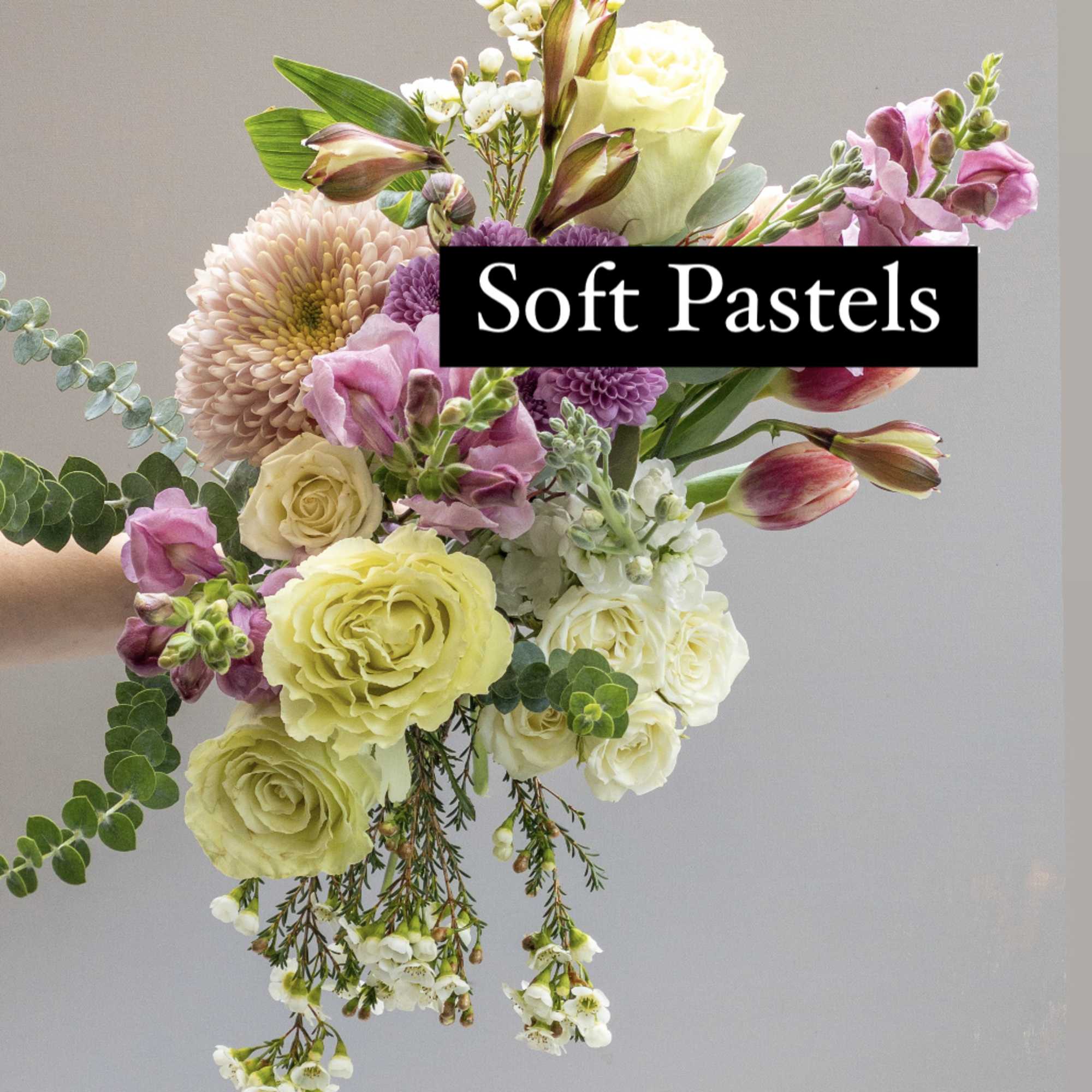 Hand-tied bouquet of pastel roses, tulips, snapdragons, and mums in pink, cream, and yellow tones