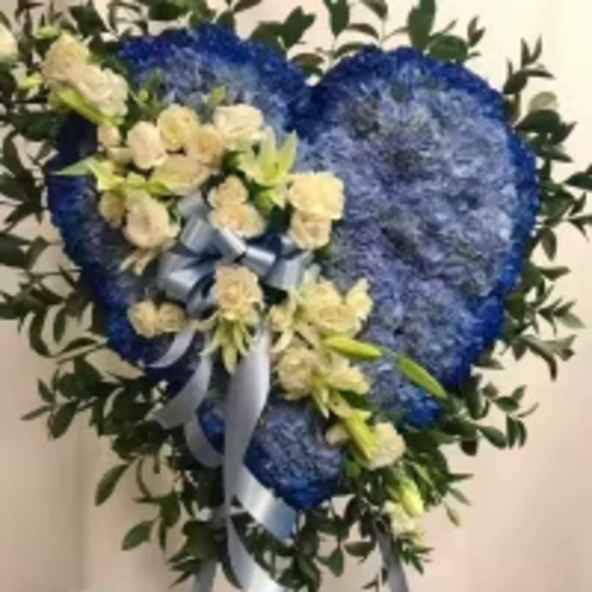 Blue heart-shaped floral wreath with cream flowers and ribbon