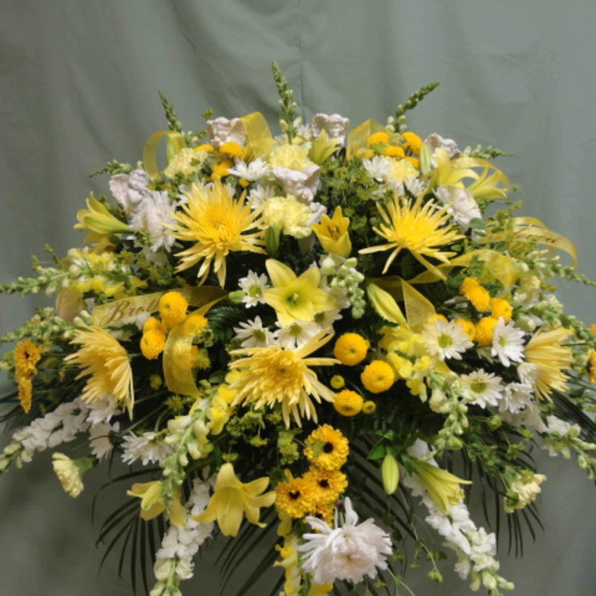 Yellow and white funeral spray with lilies and daisies