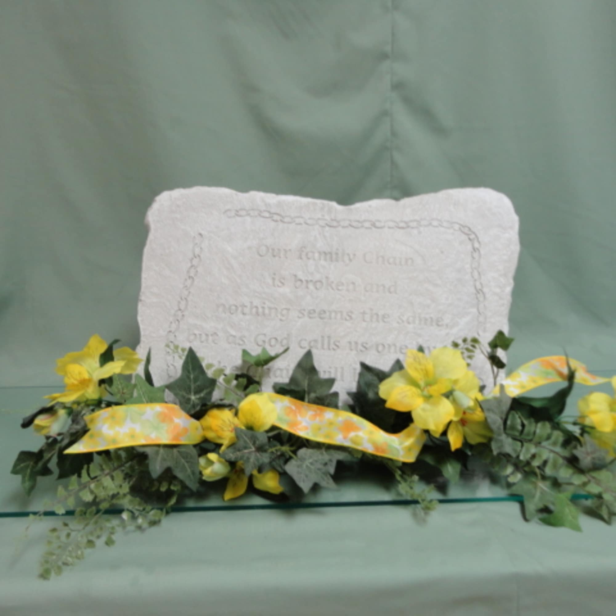 Yellow flowers and greenery arranged around a memorial pillow