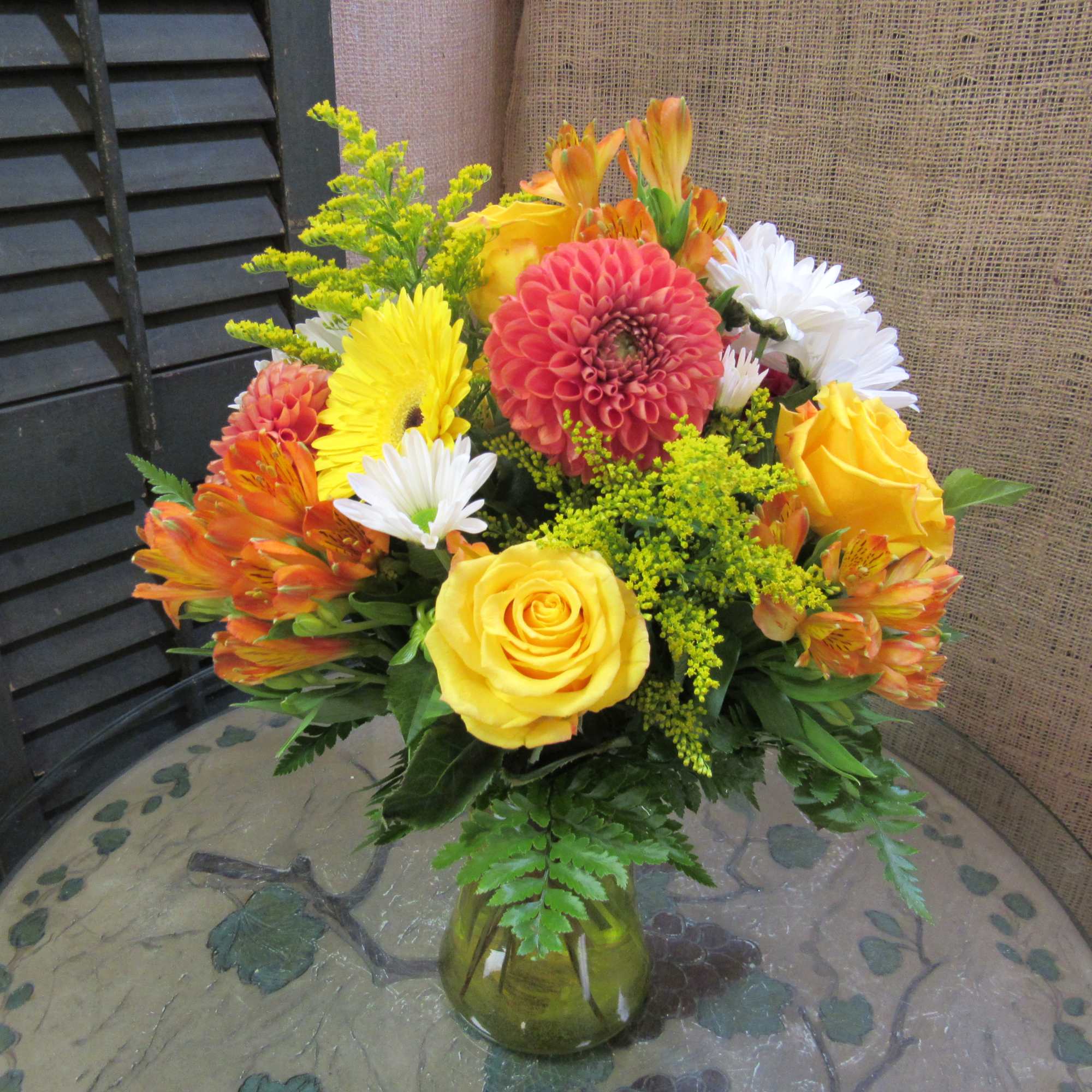 Bouquet of yellow, orange, red, and white flowers in a glass vase