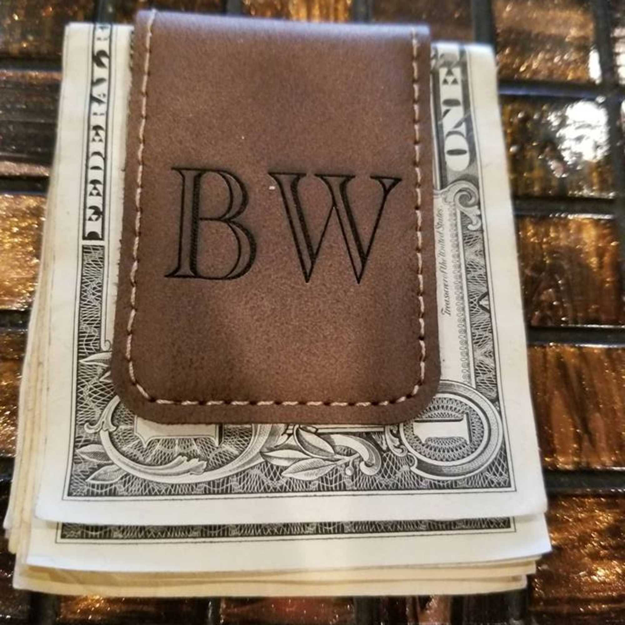 Brown leather money clip holding folded U.S. bills