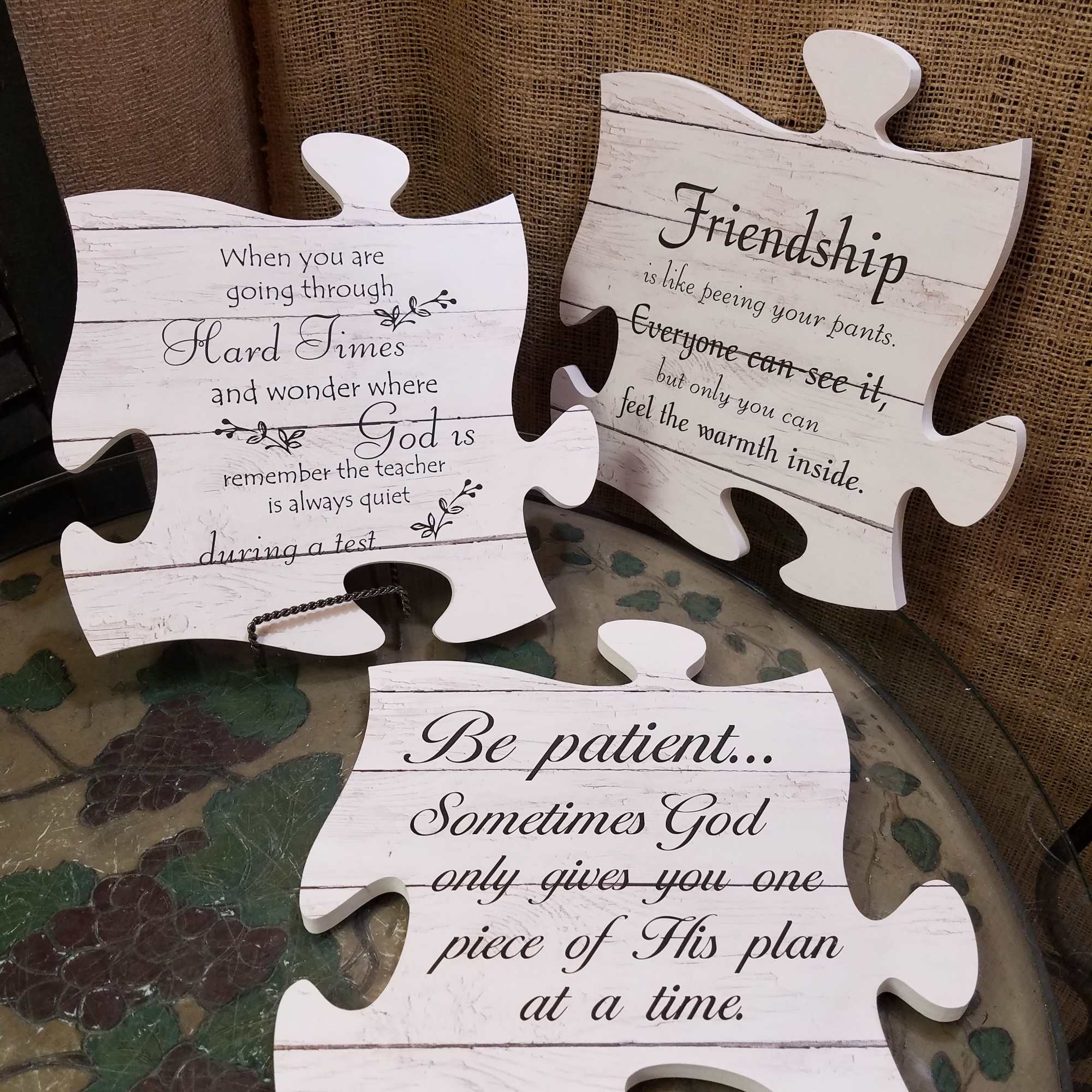 Three white puzzle-piece signs with inspirational text on a burlap backdrop