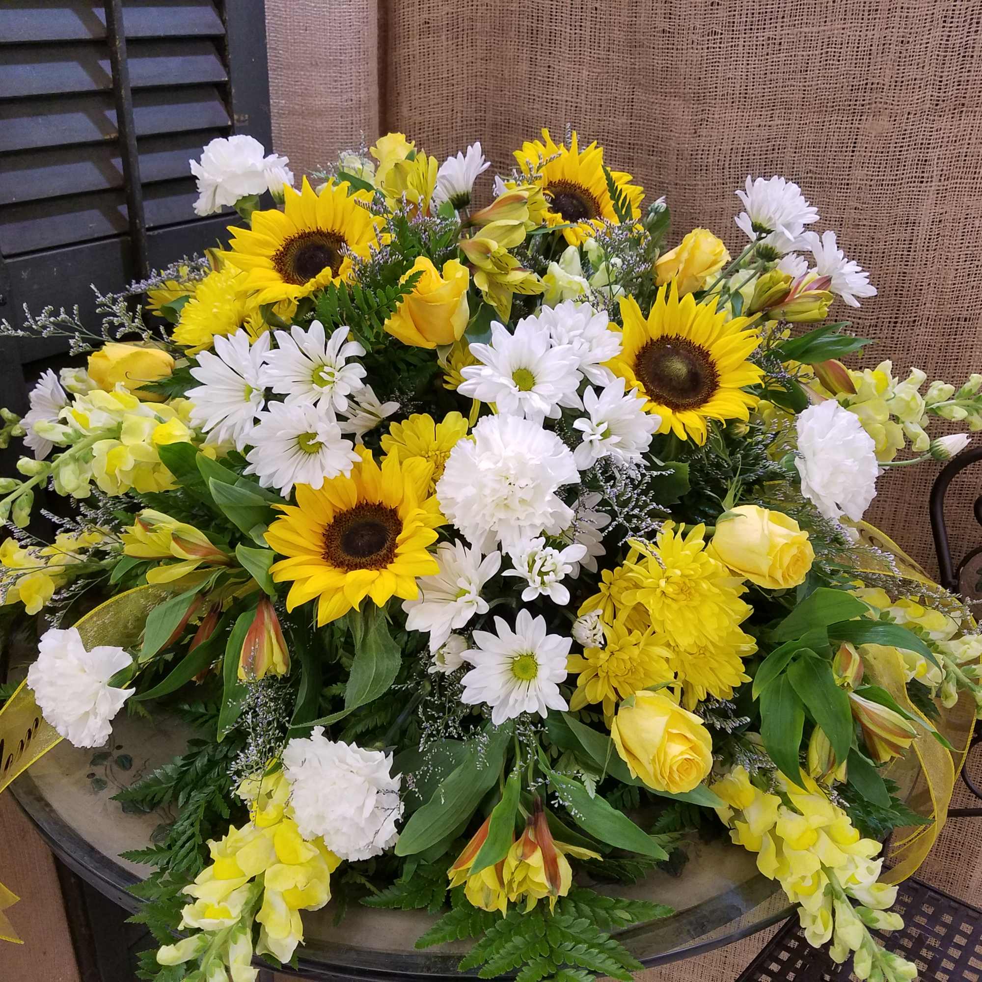 Yellow sunflowers and white daisies arranged with yellow roses in a low bouquet