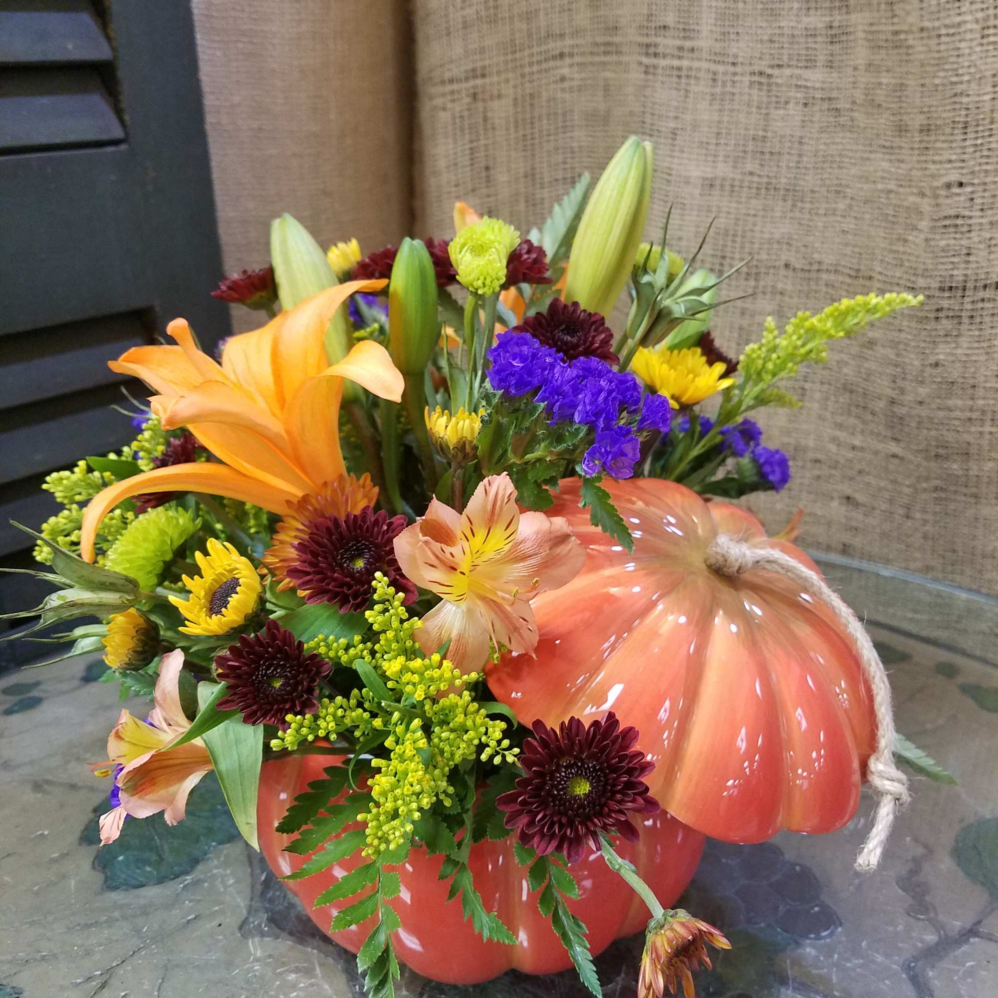 Fall floral arrangement in a pumpkin-shaped container with lilies and mums