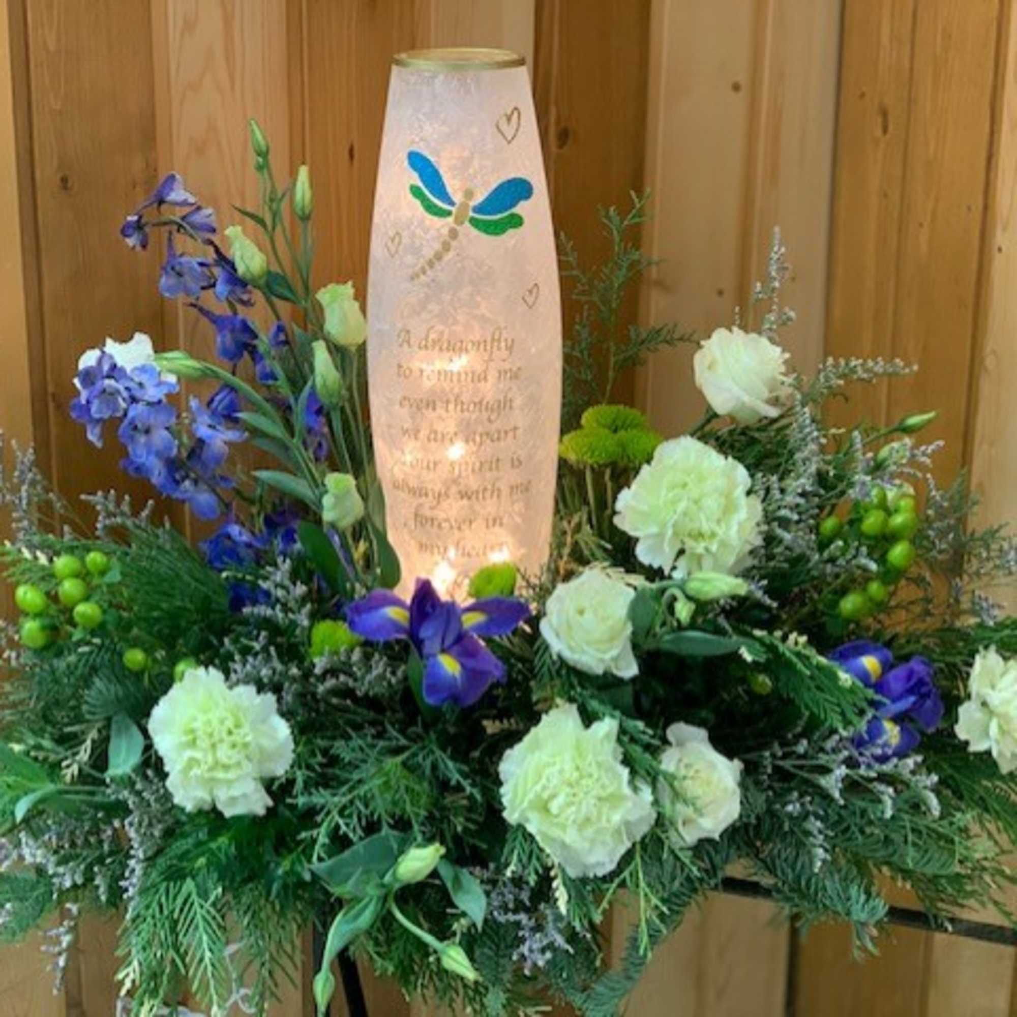 Sympathy floral arrangement with a lit memorial candle and white and purple flowers