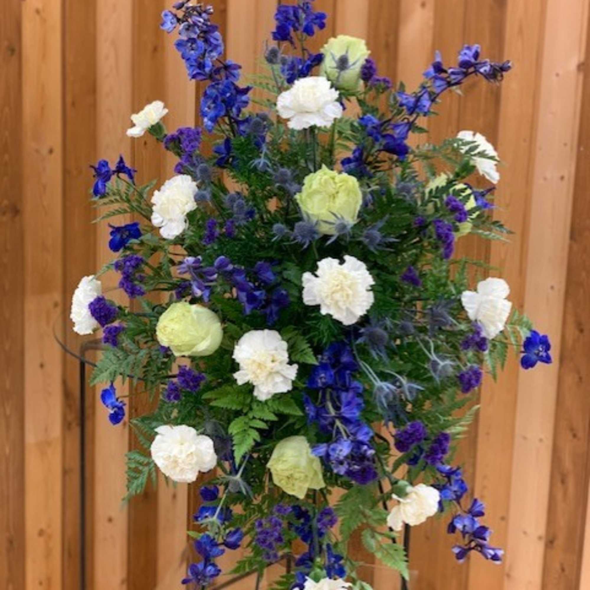 Tall blue and white floral standing spray on a metal easel