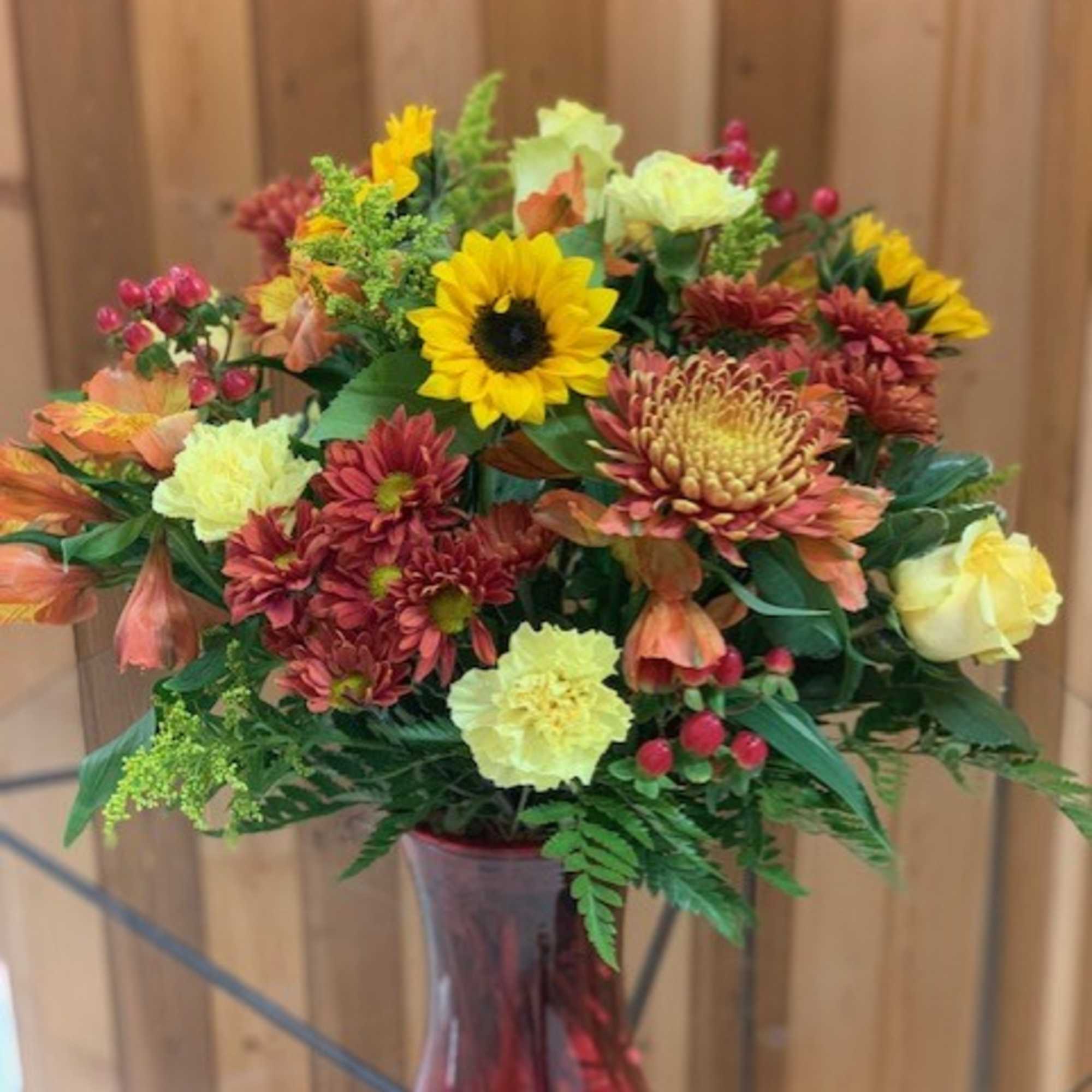 Mixed bouquet with sunflowers, chrysanthemums, and roses in a glass vase