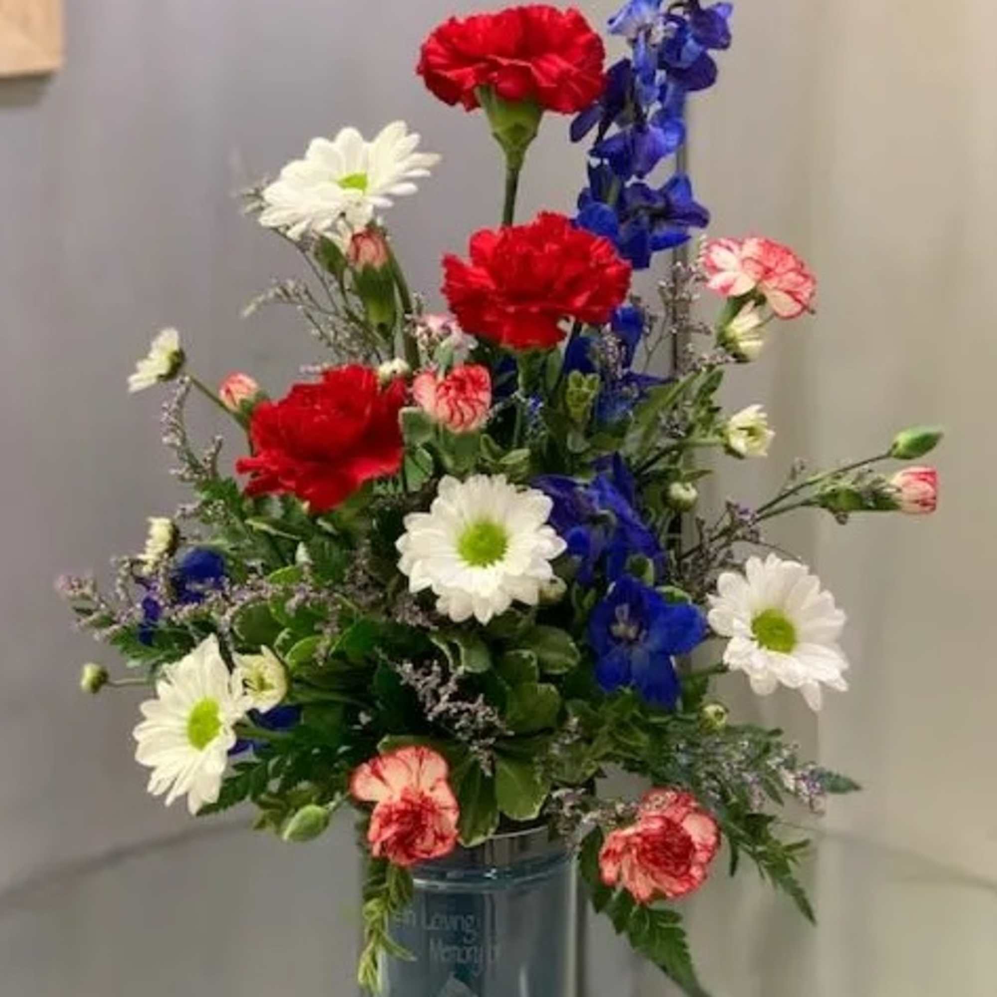 Mixed bouquet of red, white, and blue flowers in a glass vase