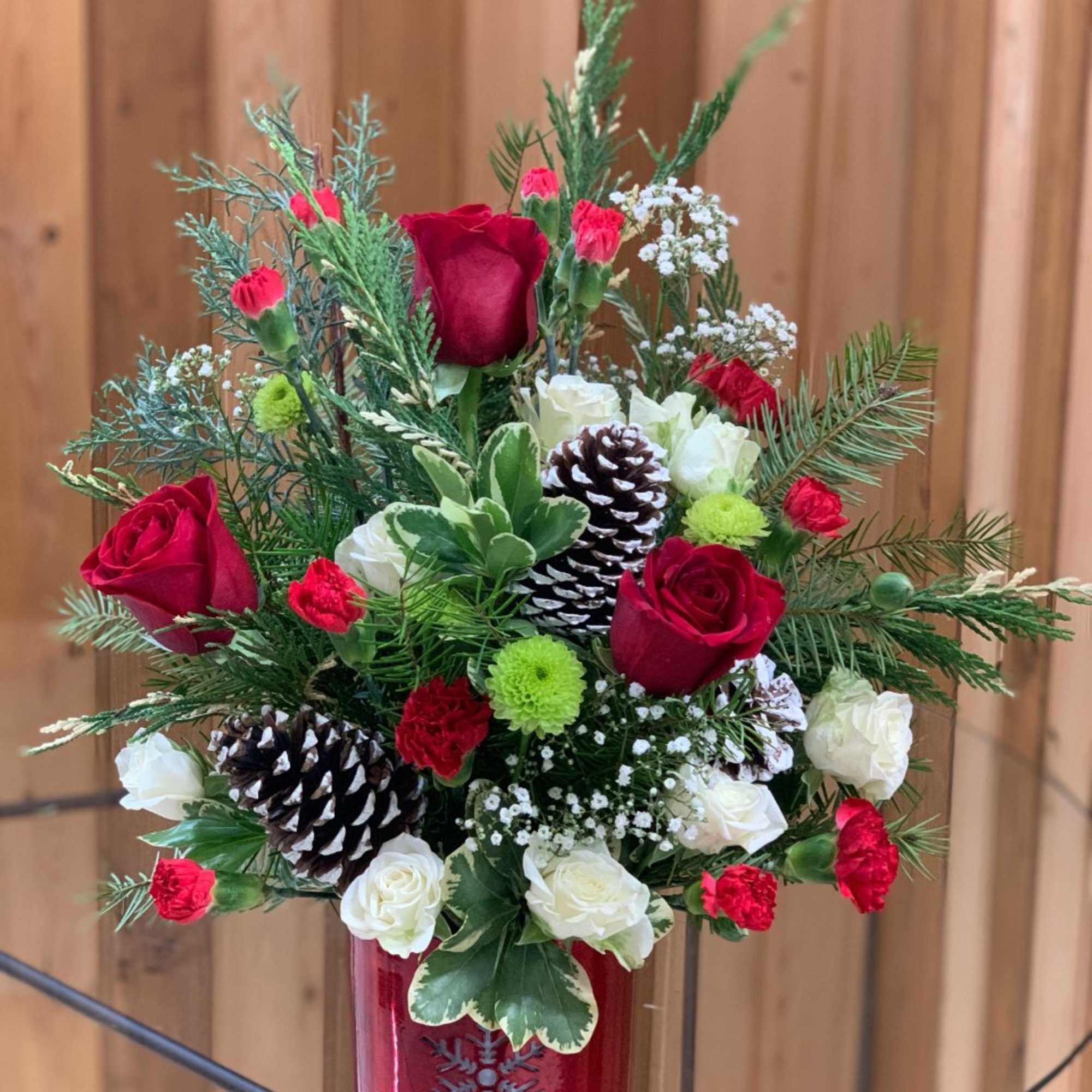 Red and white floral arrangement in a red vase with pinecones